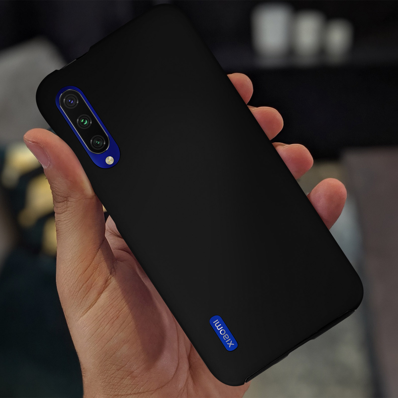 Een hand die een zwarte telefoon vasthoudt met blauwe cameradetails, Xiaomi-logo zichtbaar.