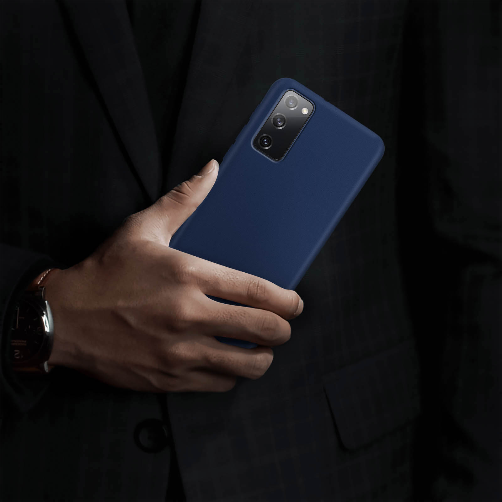 Una persona che tiene una custodia blu navy. Il telefono ha una fotocamera ed è in un abito scuro.