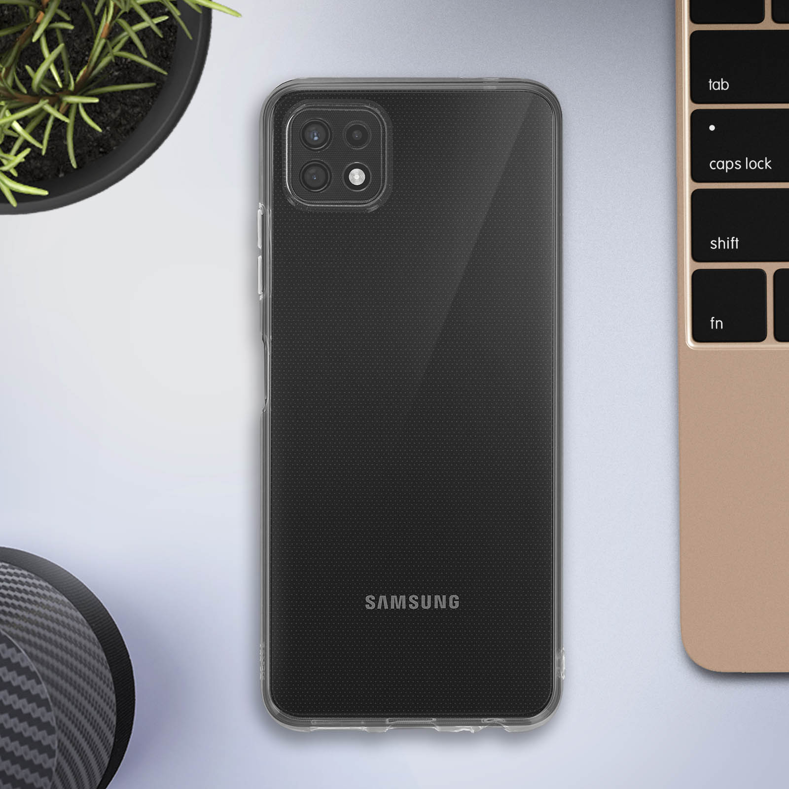 Téléphone dans un étui transparent sur un bureau avec un ordinateur portable et une plante.