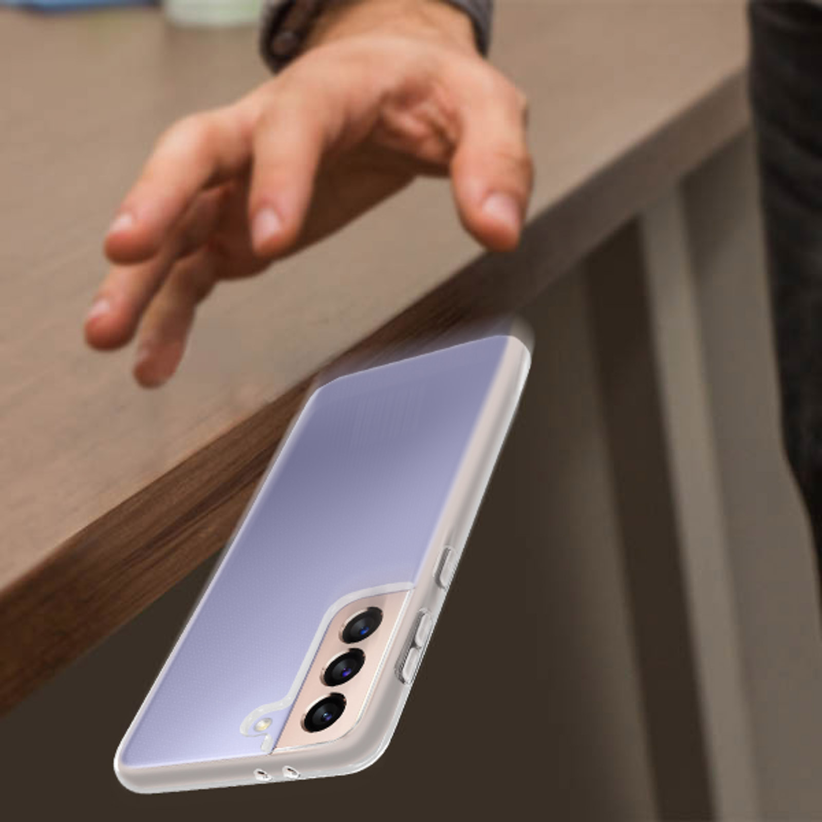 Una mano sembra far cadere un telefono su un tavolo, in uno sfondo sfocato.