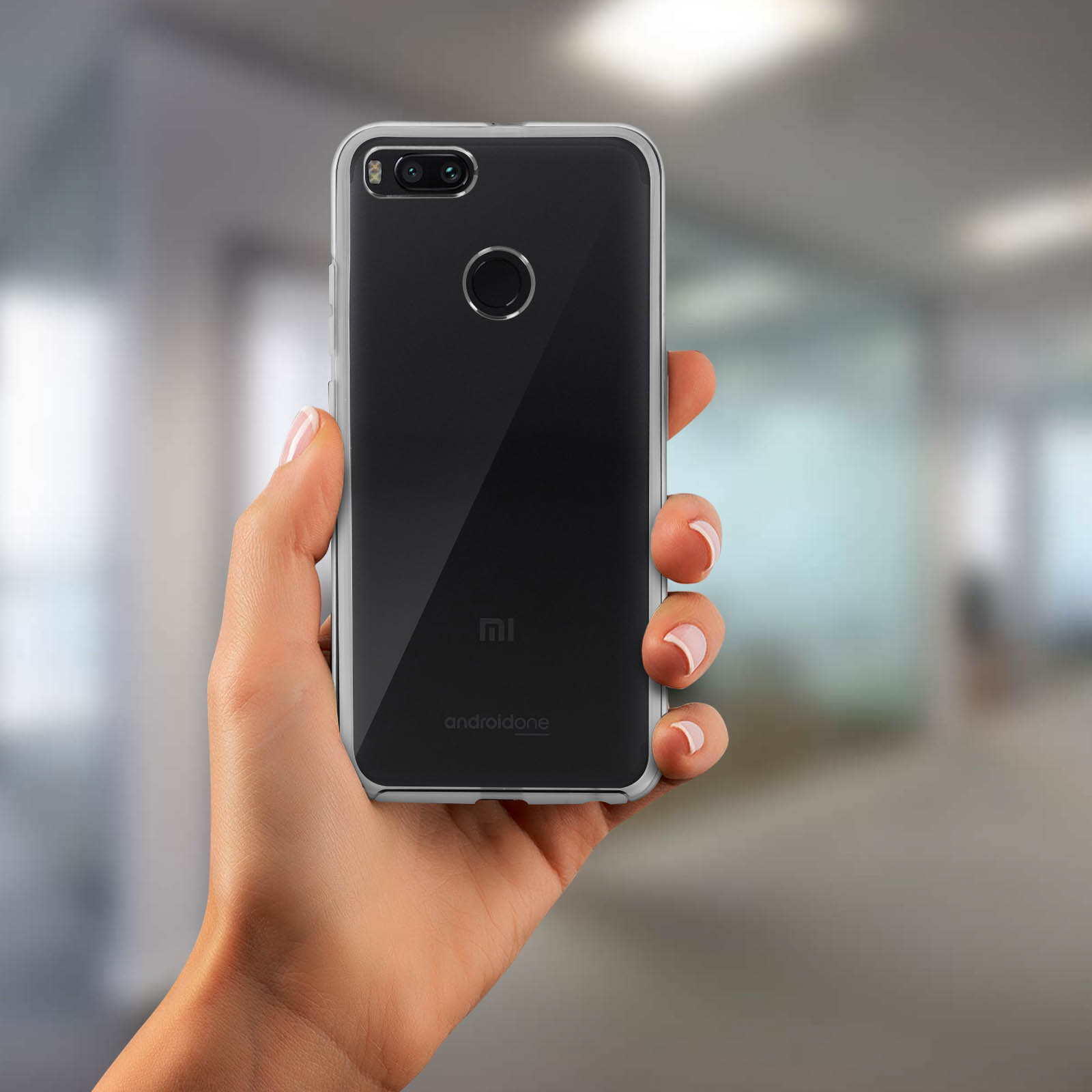 Una mano che tiene uno smartphone nero con una custodia trasparente. Lo sfondo è sfocato.