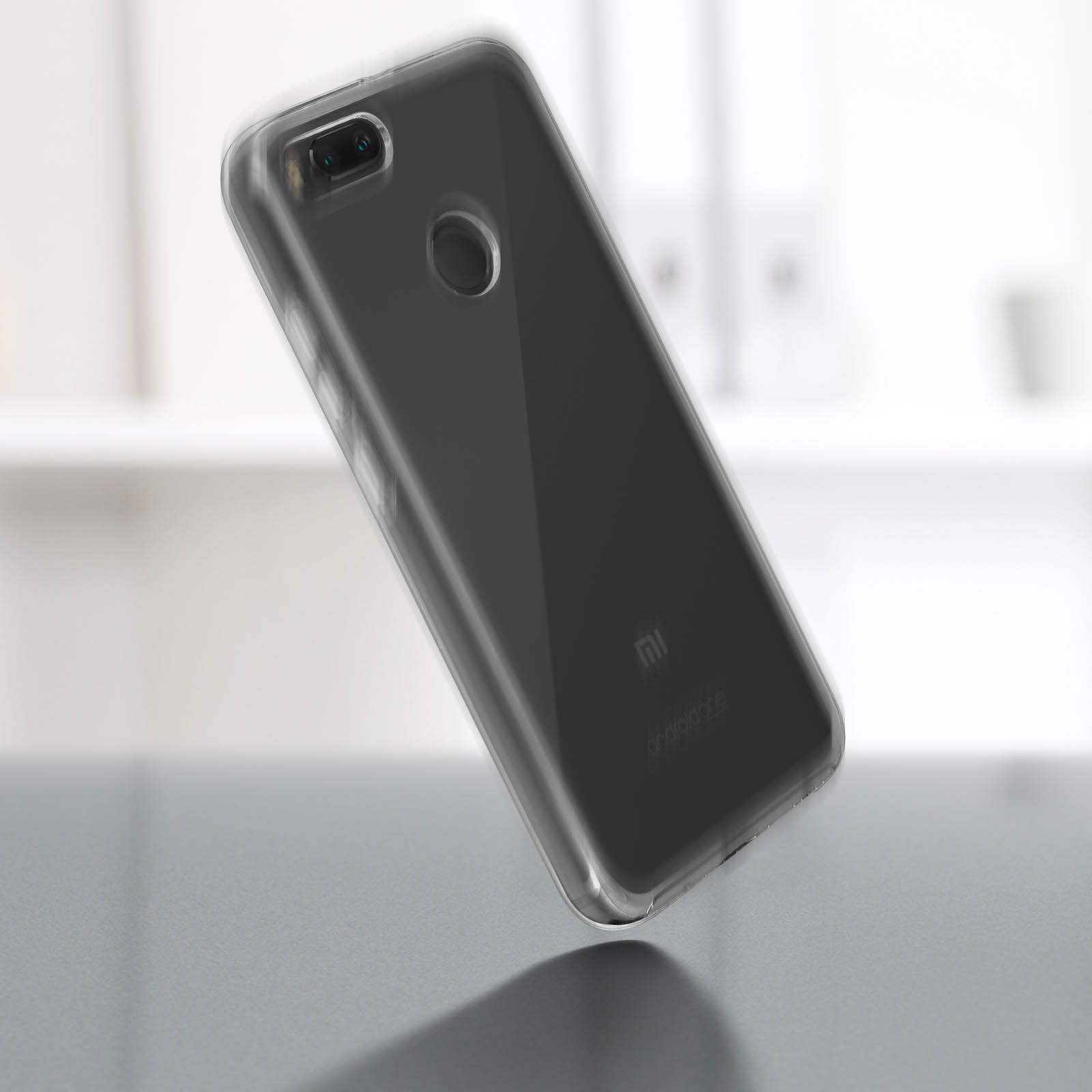 Uno smartphone nero con custodia trasparente su superficie grigia, leggermente angolato.