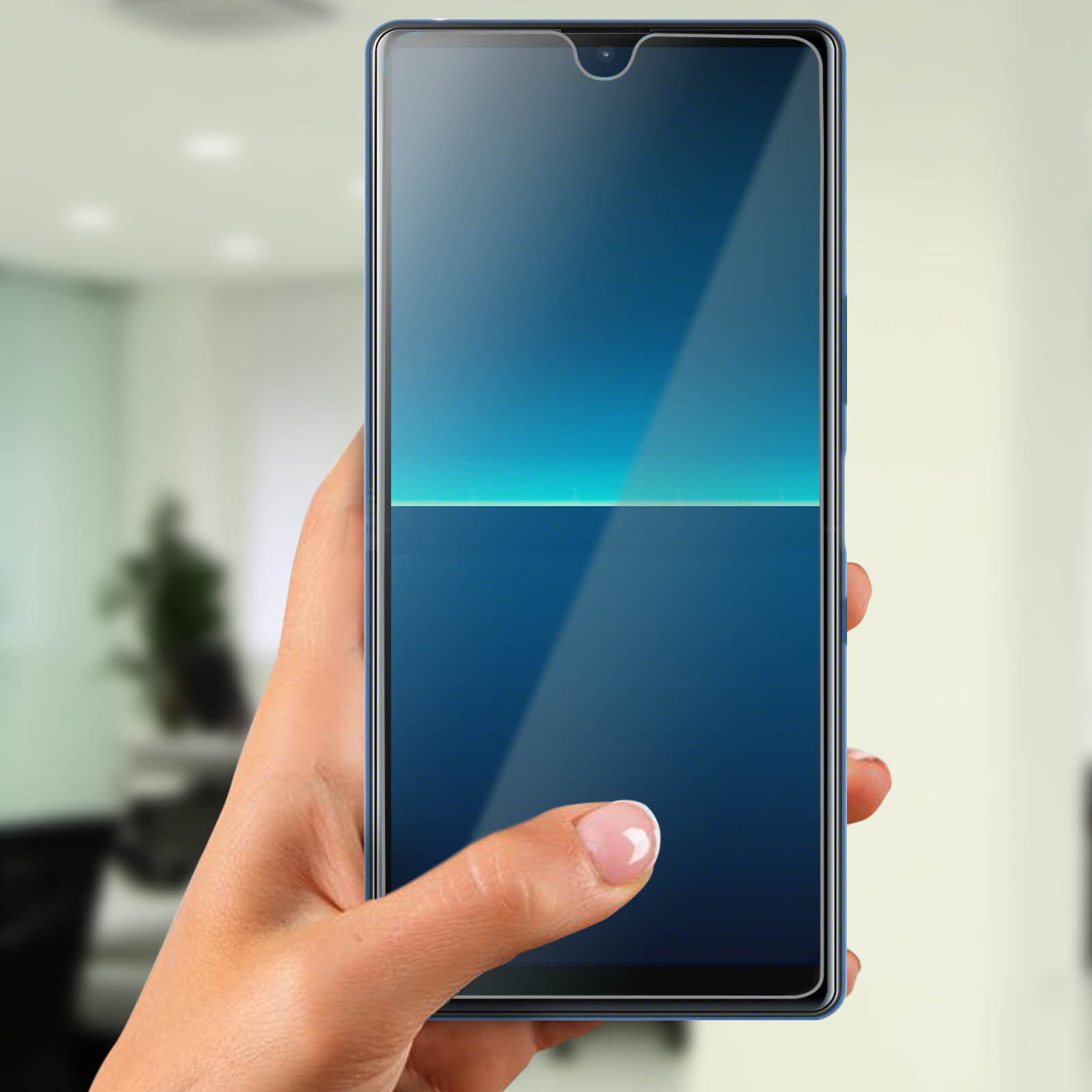 Mano che tiene uno smartphone blu con protezione schermo. Lo schermo è blu, con una linea bianca. Sfondo sfocato.