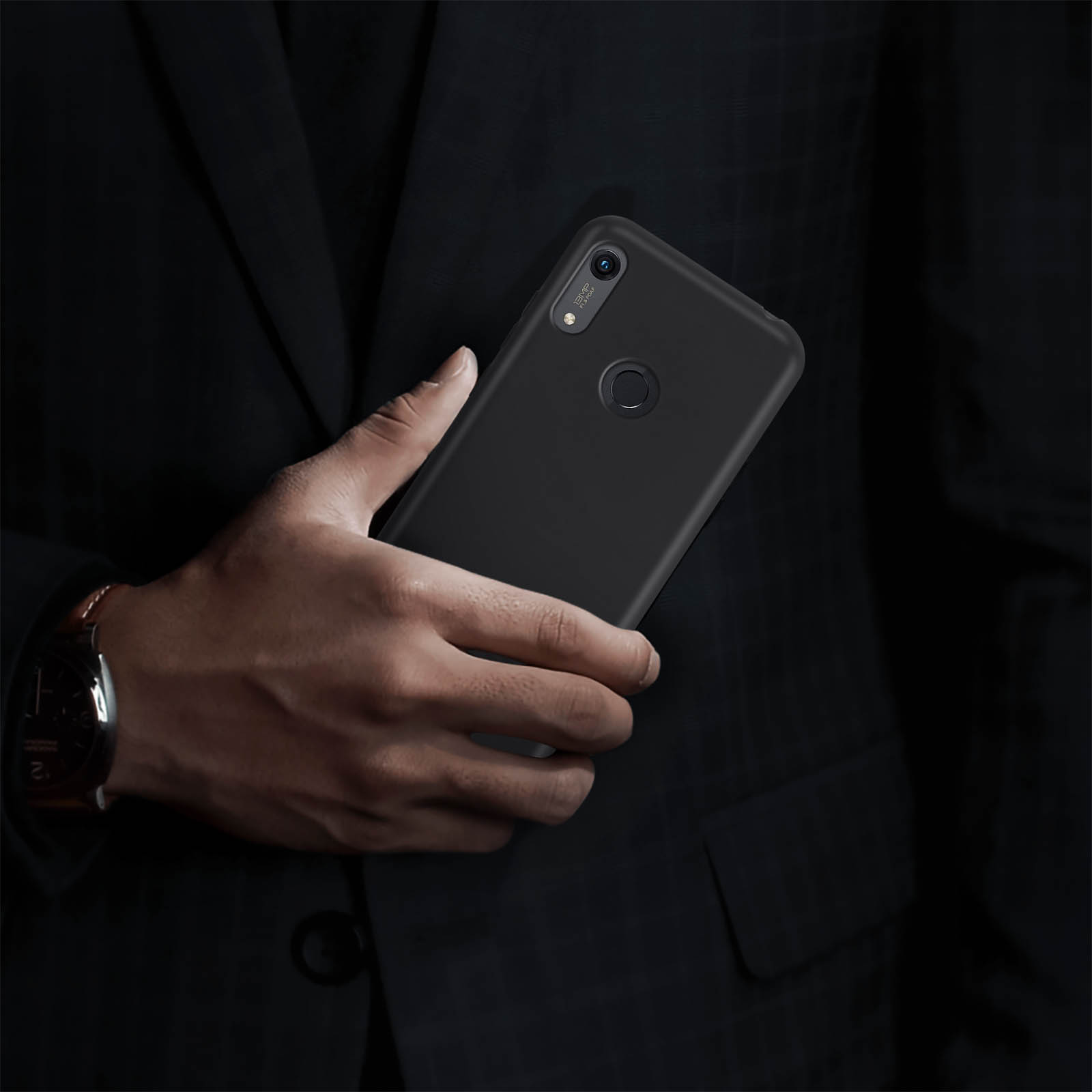 Una persona che tiene in mano uno smartphone nero in un abito scuro. Il telefono mostra una fotocamera e una cover.