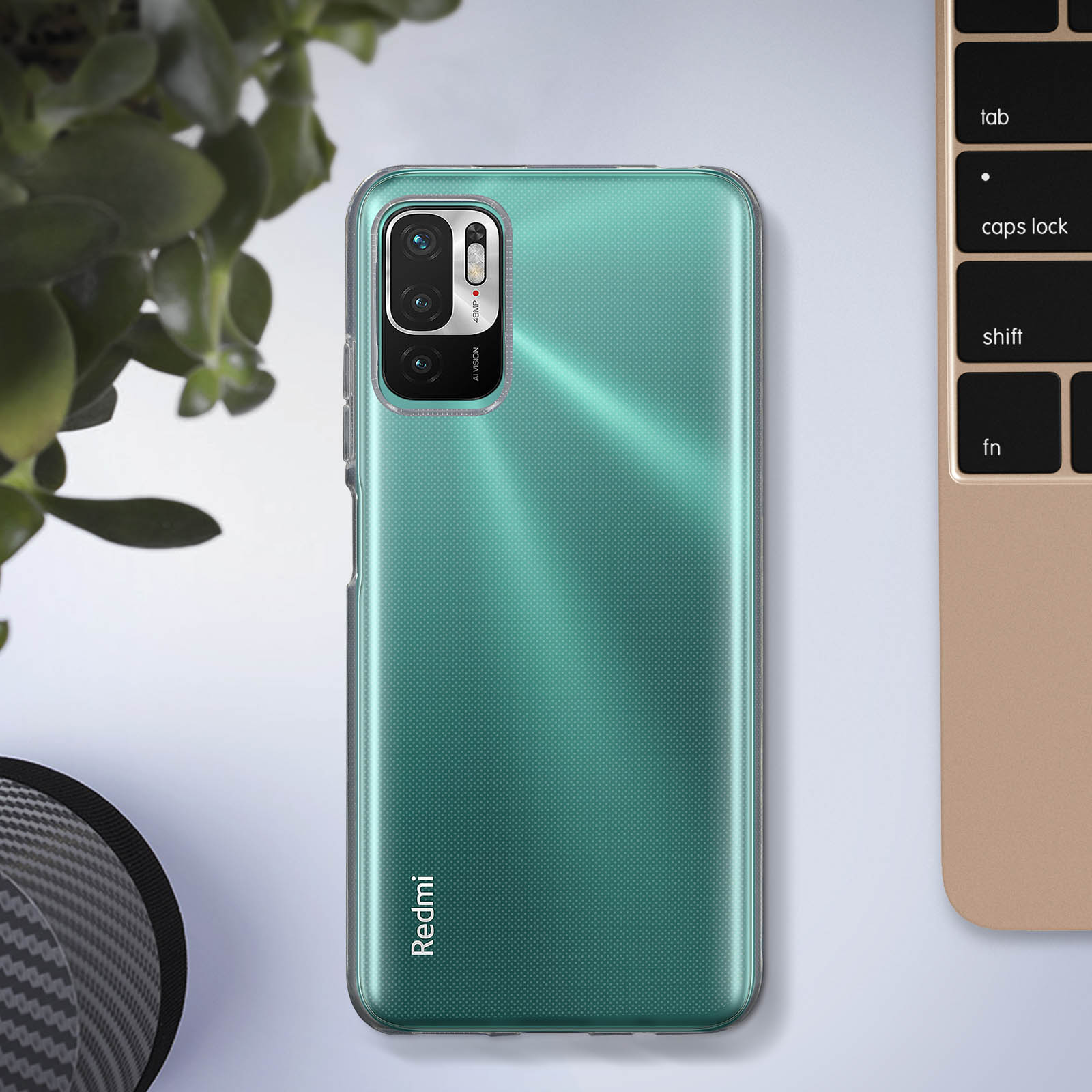 Coque de téléphone verte sur une table, avec clavier et plante en arrière-plan.
