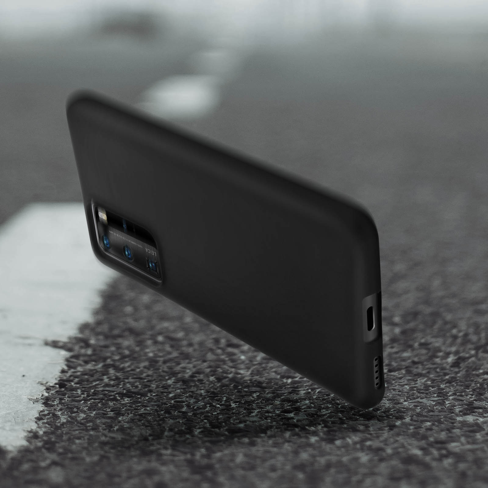 Una custodia nera per telefono su una superficie ruvida. Ha una fotocamera e una porta laterale.