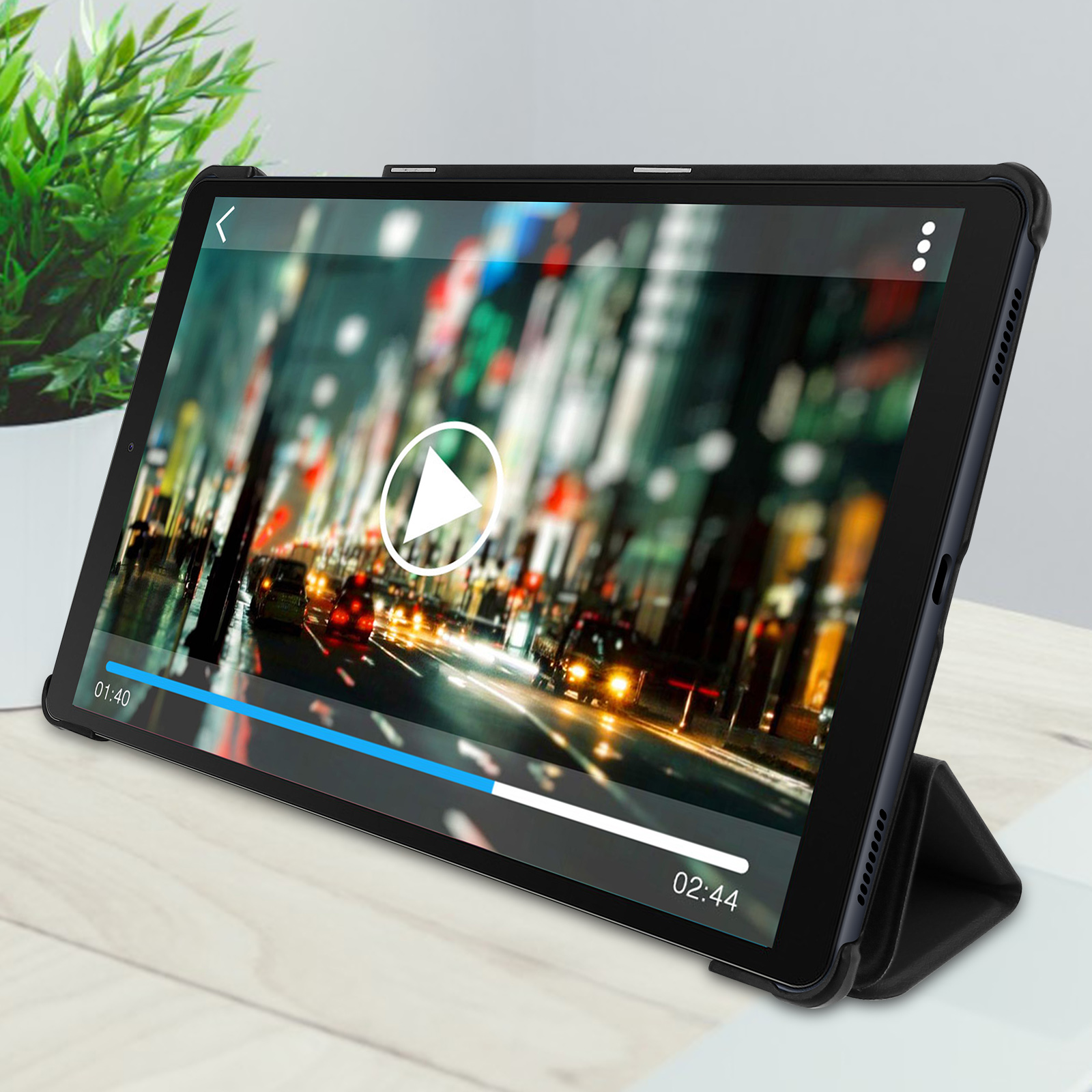 Tablet che riproduce un video su un tavolo di legno con una pianta.