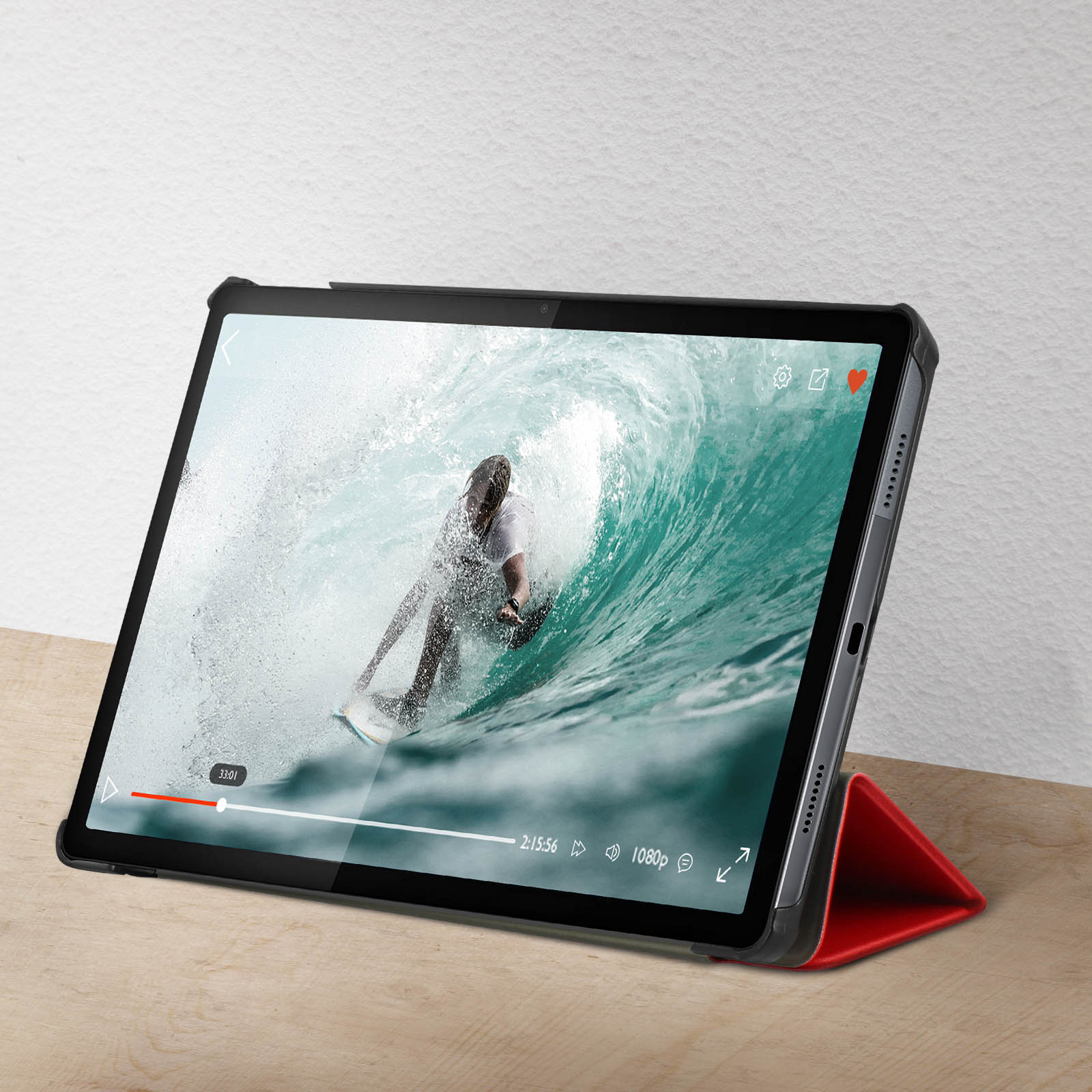 Tablet che mostra un video di surf, con supporto rosso su superficie di legno.