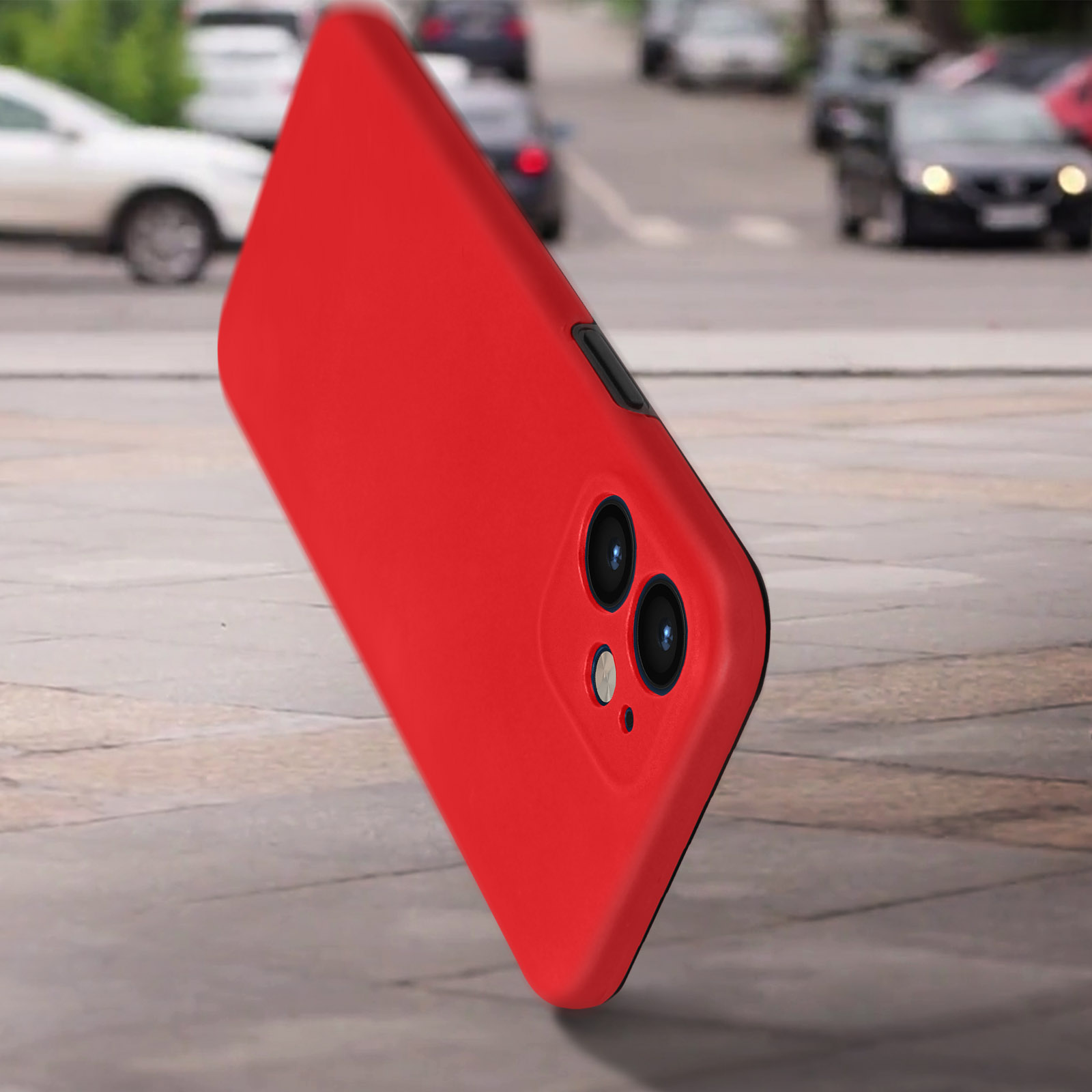 Una custodia per telefono rossa in una strada. Il telefono ha doppie lenti della fotocamera. Lo sfondo è sfocato.