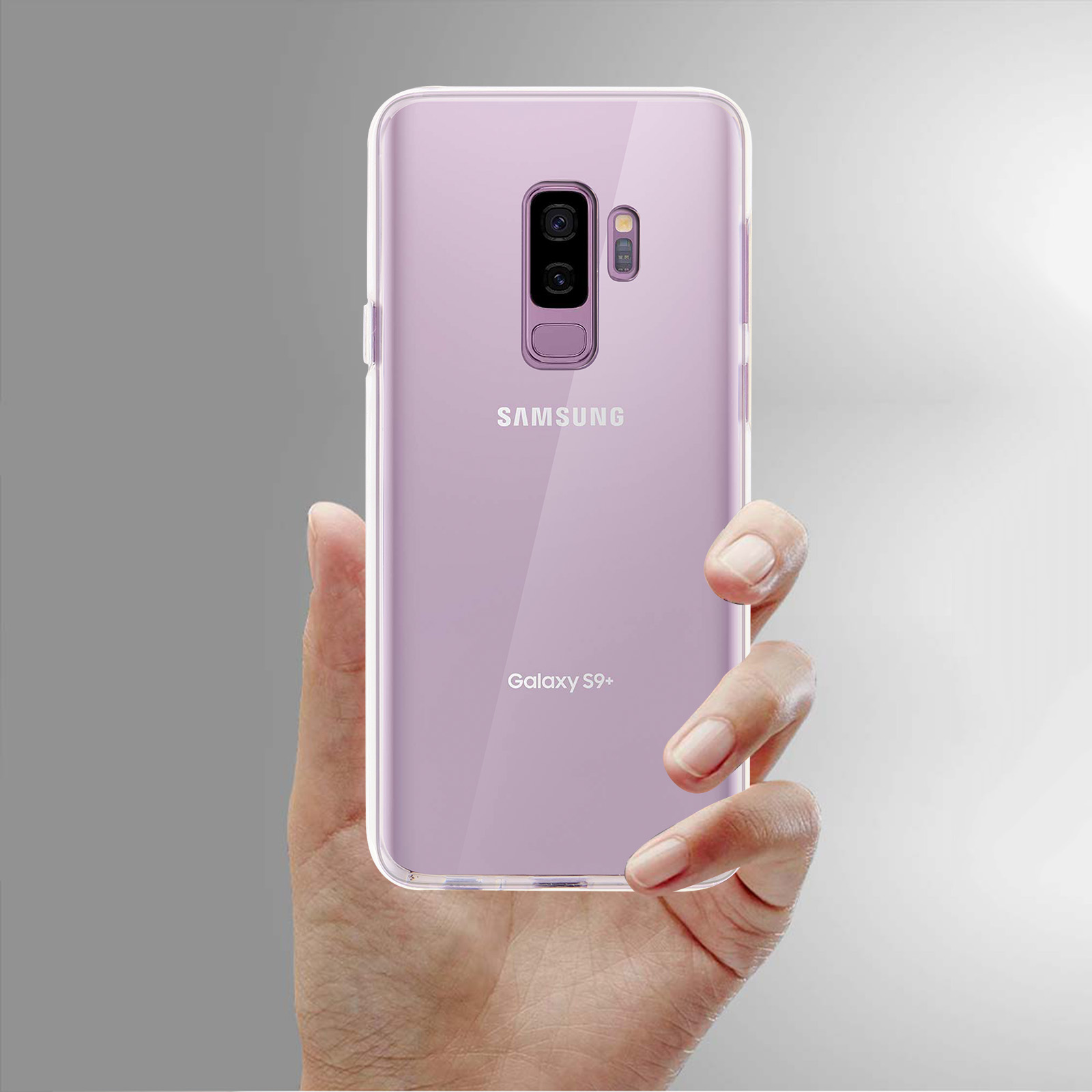 Una mano che tiene un telefono in una custodia trasparente. Sfondo grigio. Telefono viola.