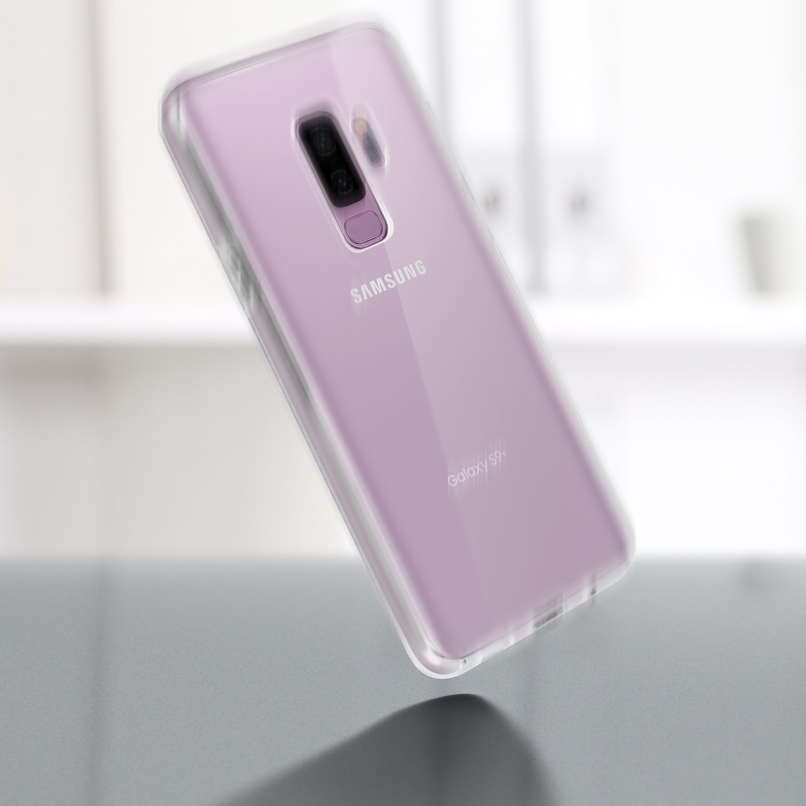 Un telefono in una custodia trasparente. Il telefono è rosa e ha una doppia fotocamera. Scrivania sullo sfondo.