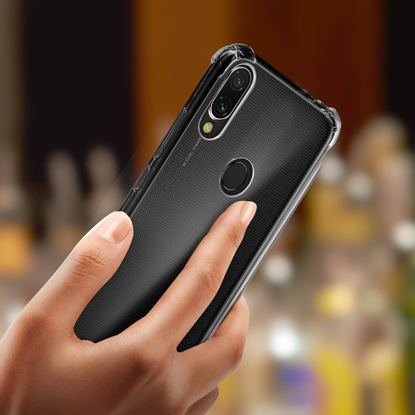 Mano che tiene un telefono in una custodia trasparente. Il telefono è nero, la custodia è trasparente.