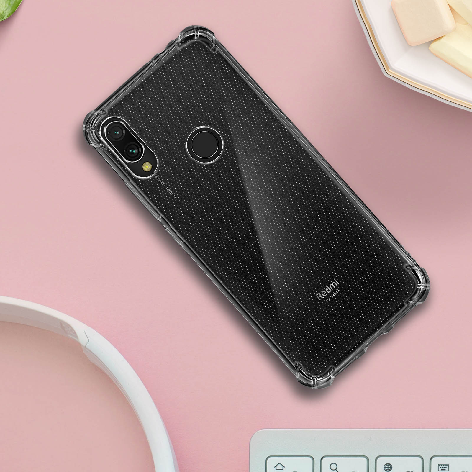 Custodia trasparente per telefono con puntini neri, fotocamera e pulsanti del telefono. Posizionata su una superficie rosa.