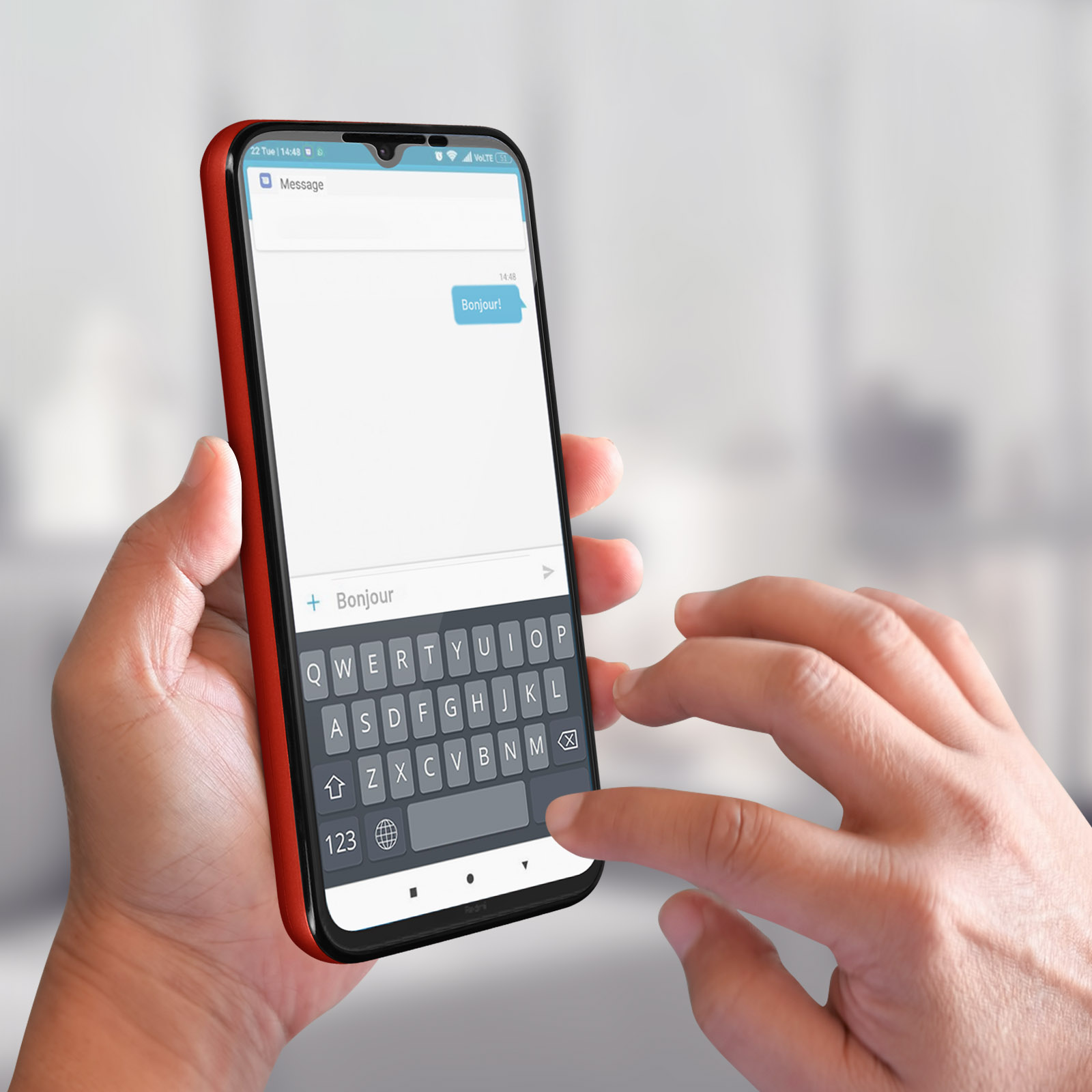 Une main tient un téléphone avec une coque rouge, affichant un message en français, avec un clavier.