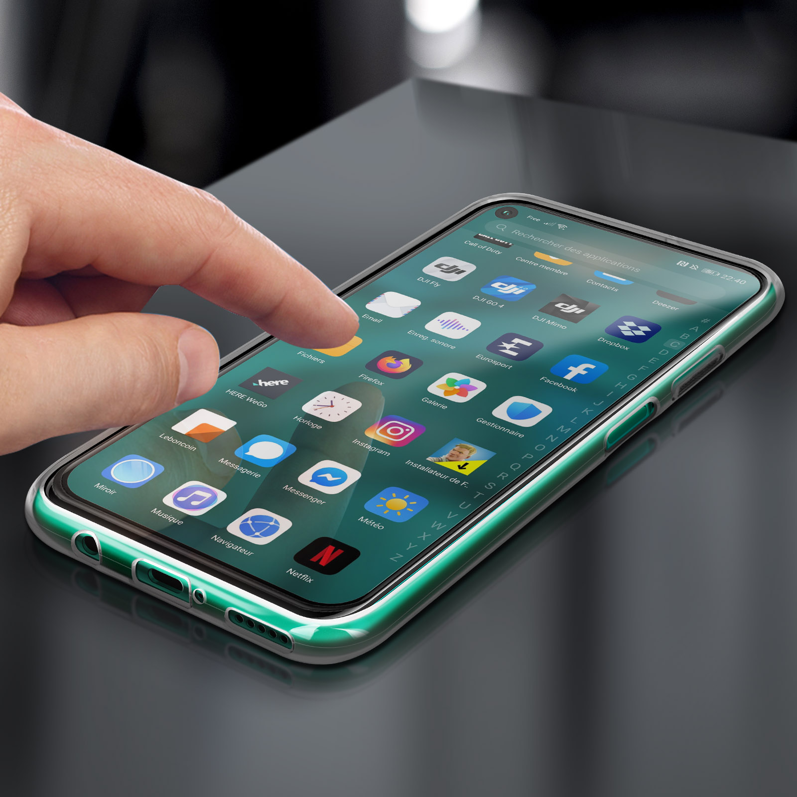 Main touchant l'écran du téléphone avec des applications. Le téléphone est dans un étui vert transparent. Fond sombre.