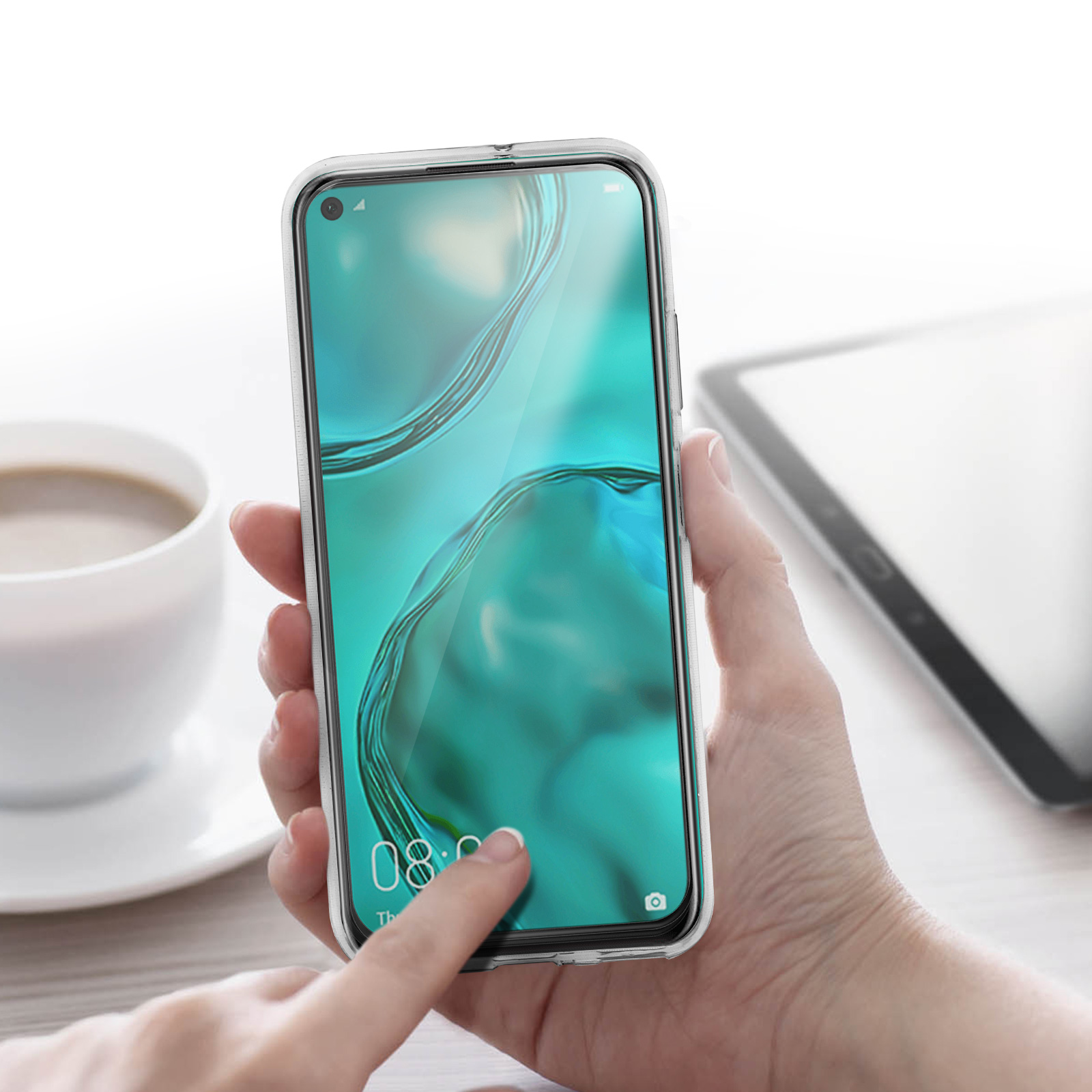 Eine Hand hält ein Telefon mit angebrachter Displayschutzfolie, mit einer Kaffeetasse im Hintergrund.