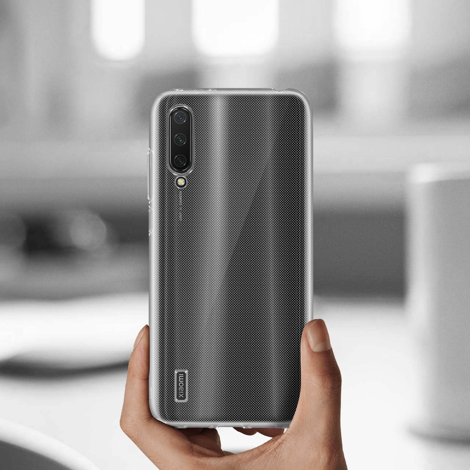 Una mano tiene un telefono con una cover nera a pois.