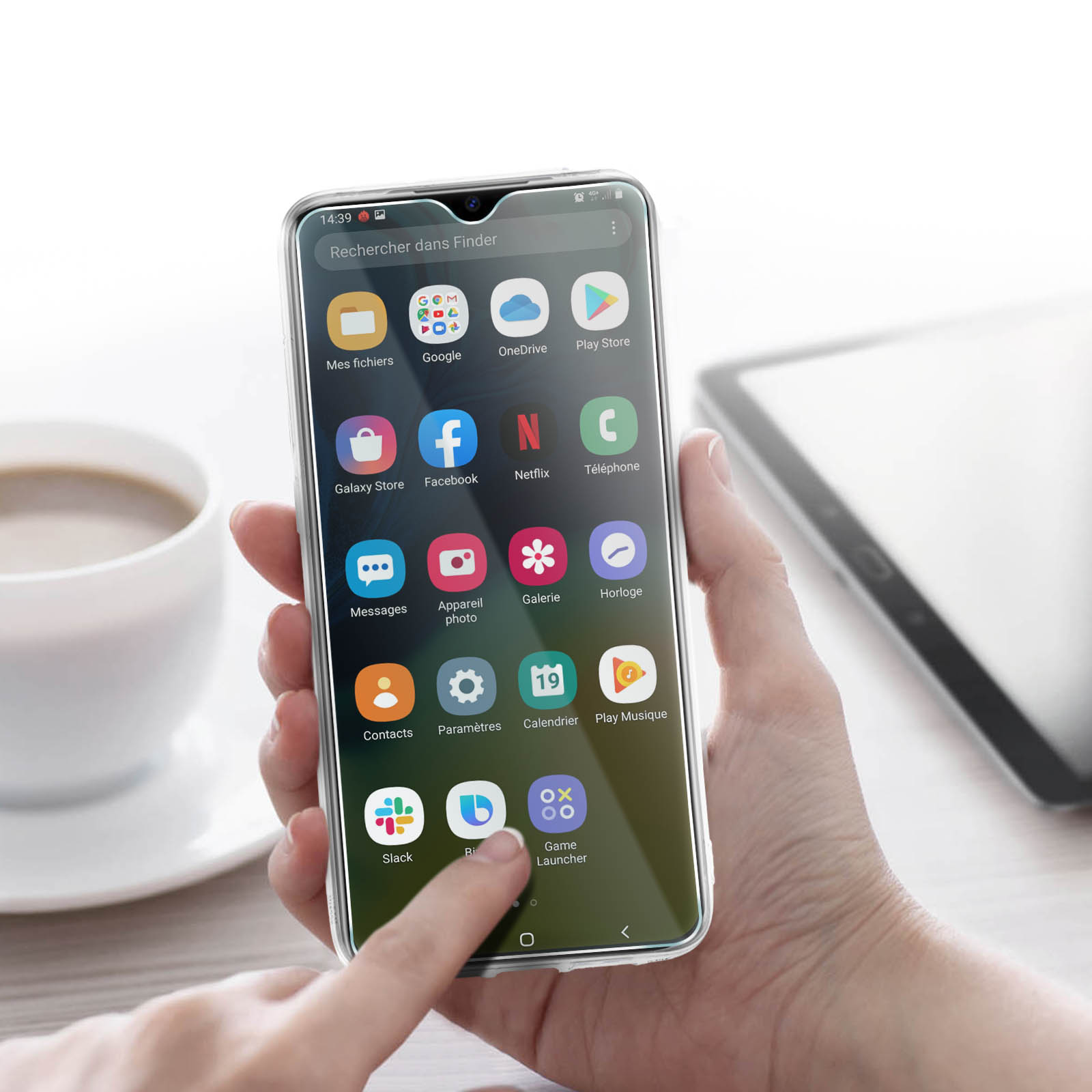 Una mano che tiene un telefono che mostra un menu di app. Tazza di caffè e tablet sullo sfondo.