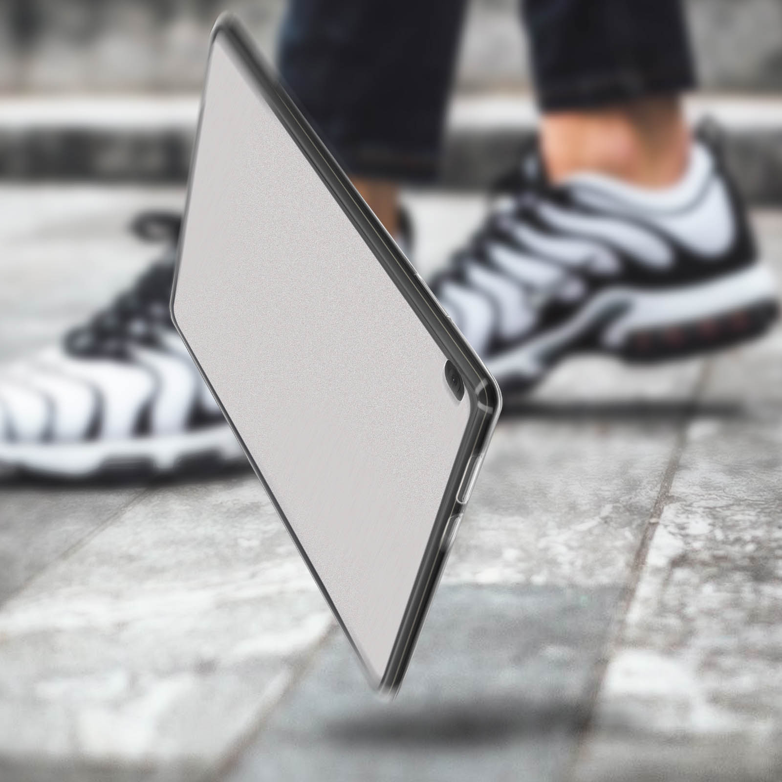 Transparente Tablet-Hülle schräg, verschwommener Hintergrund mit Person in Turnschuhen.