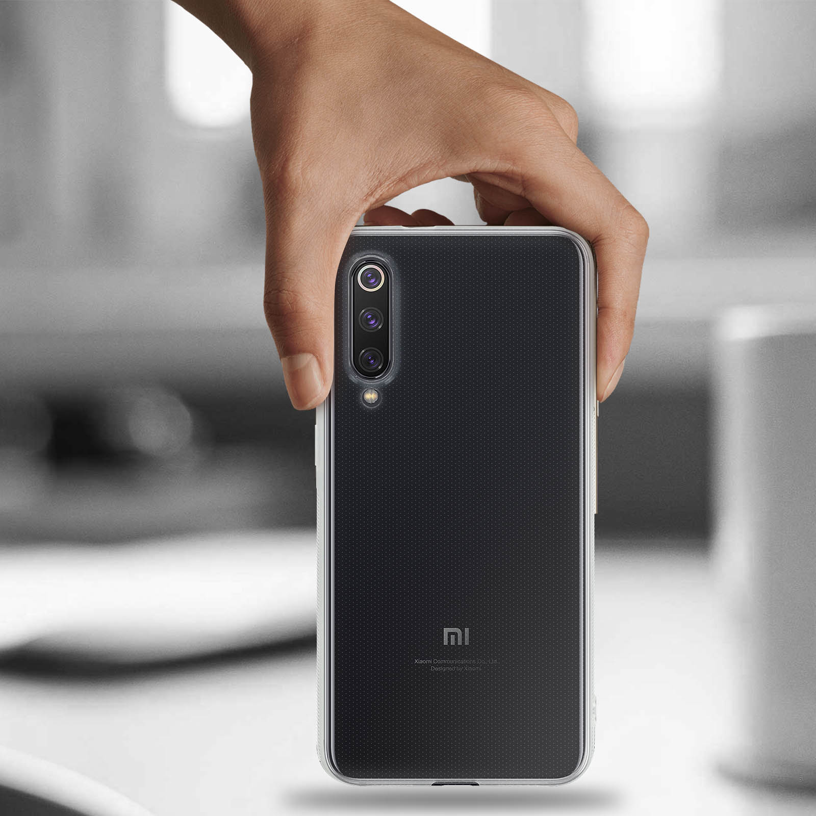 Una mano tiene un telefono nero in una custodia trasparente. Il telefono ha una fotocamera.