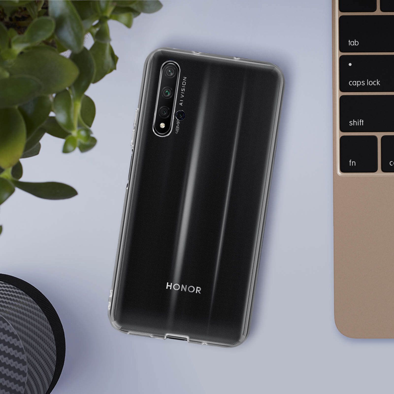 Un telefono nero con una custodia trasparente appoggiato su un tavolo vicino a una pianta.