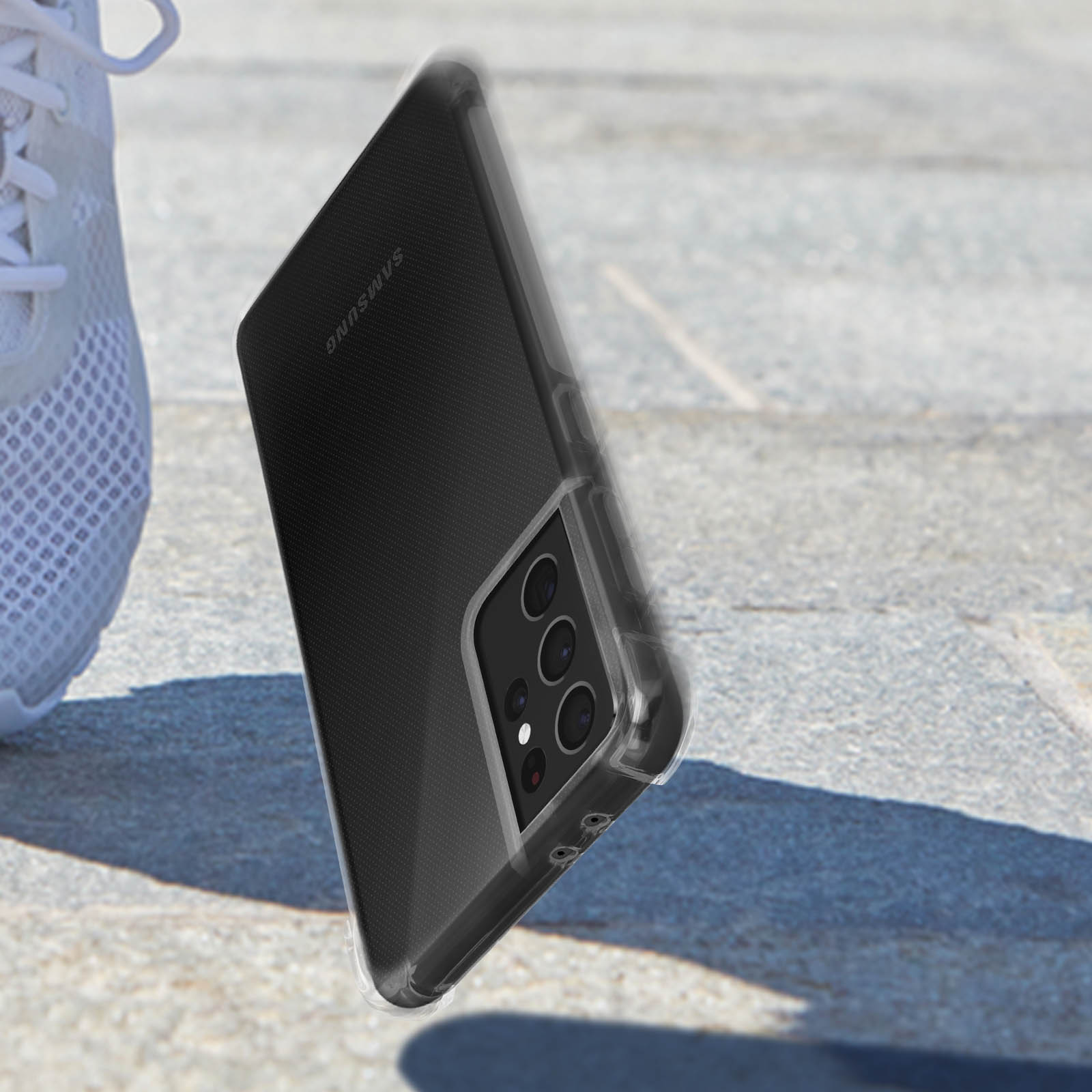 Un telefono in una custodia trasparente inclinato, che mostra la fotocamera e il logo Samsung, sfondo sfocato.