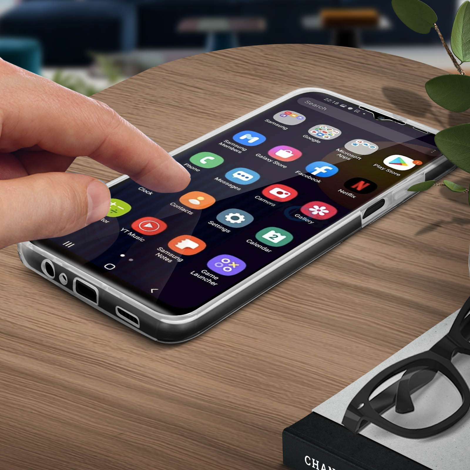Main touchant l'écran d'un téléphone avec des icônes d'applications. Téléphone sur table en bois.