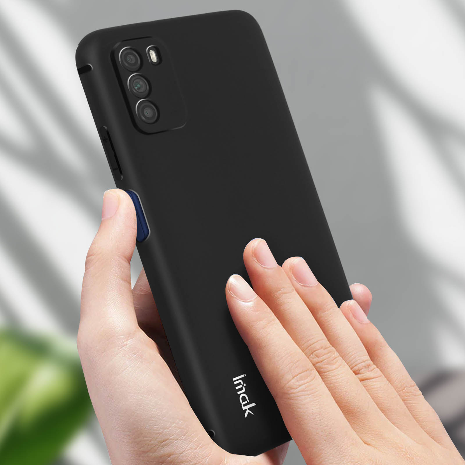 Mano che tiene una custodia nera per telefono. La custodia ha tre fotocamere e il marchio 'imakk'.