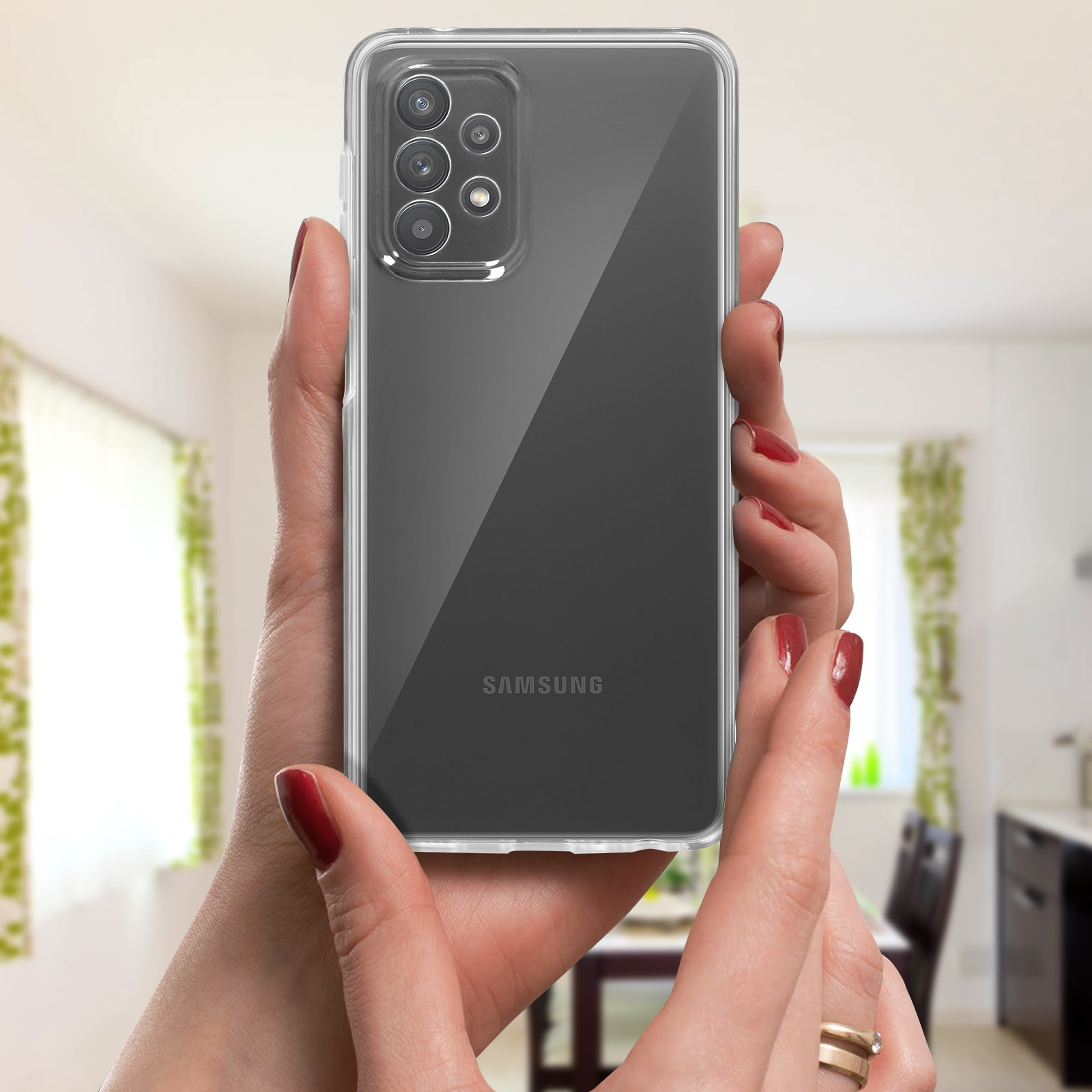 Mains tenant un téléphone Samsung dans une coque transparente. Vernis à ongles rouge.