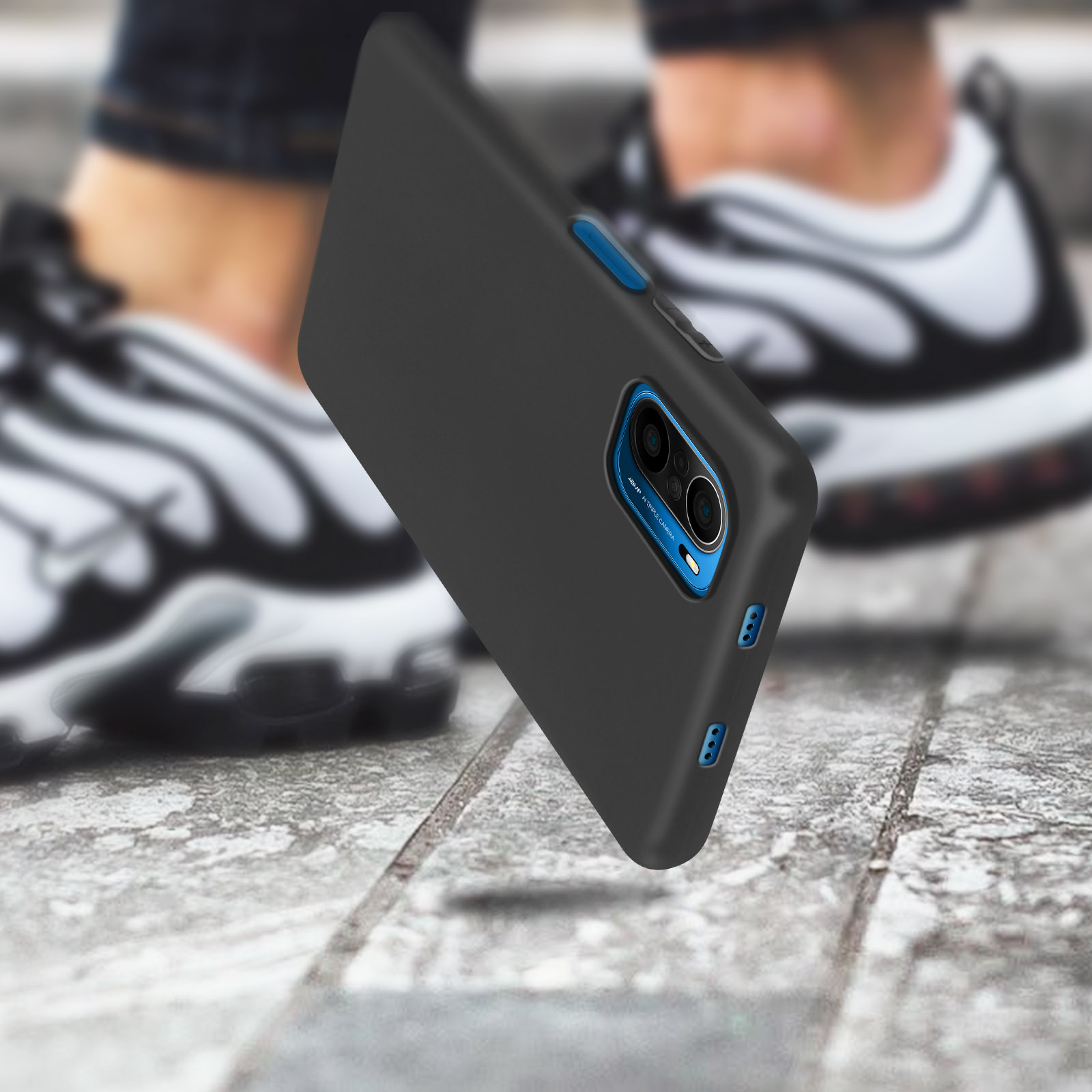 Una custodia nera per telefono viene mostrata con un telefono. Il telefono sembra cadere. Le scarpe da ginnastica sono sullo sfondo.