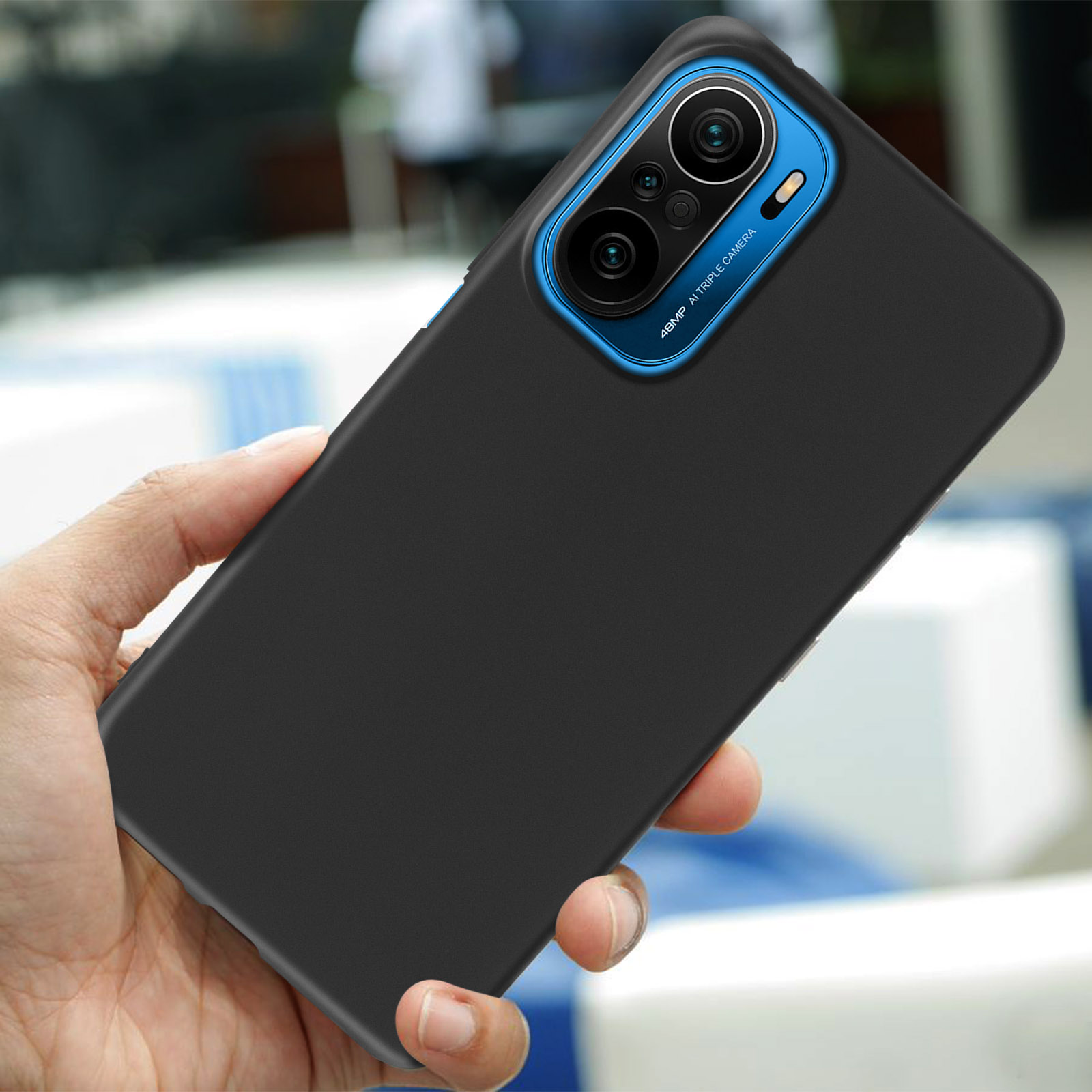 Una custodia nera per telefono con un anello blu per la fotocamera. La custodia viene tenuta.