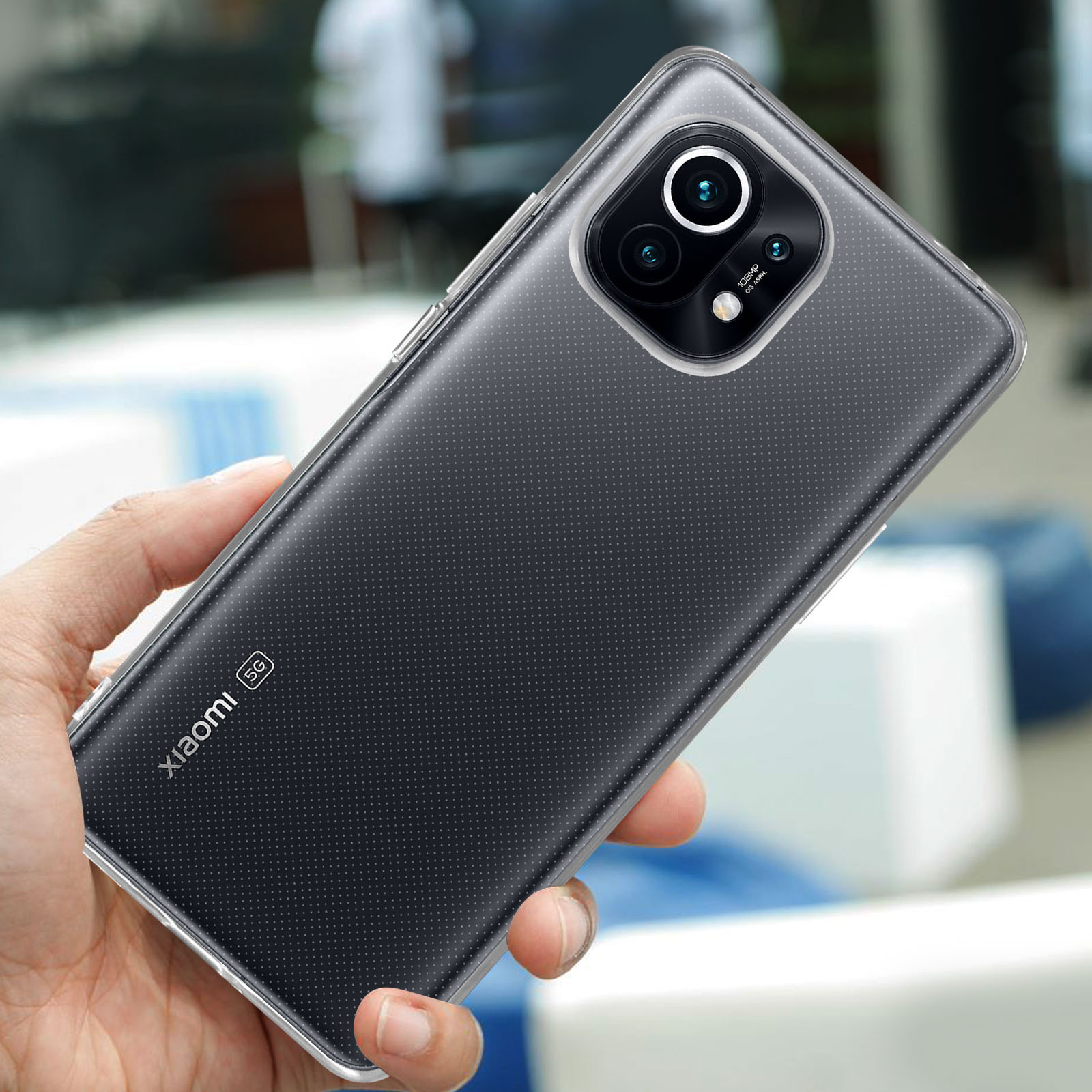 Una mano tiene in mano un telefono con una custodia trasparente. Il retro del telefono è nero, con una fotocamera.