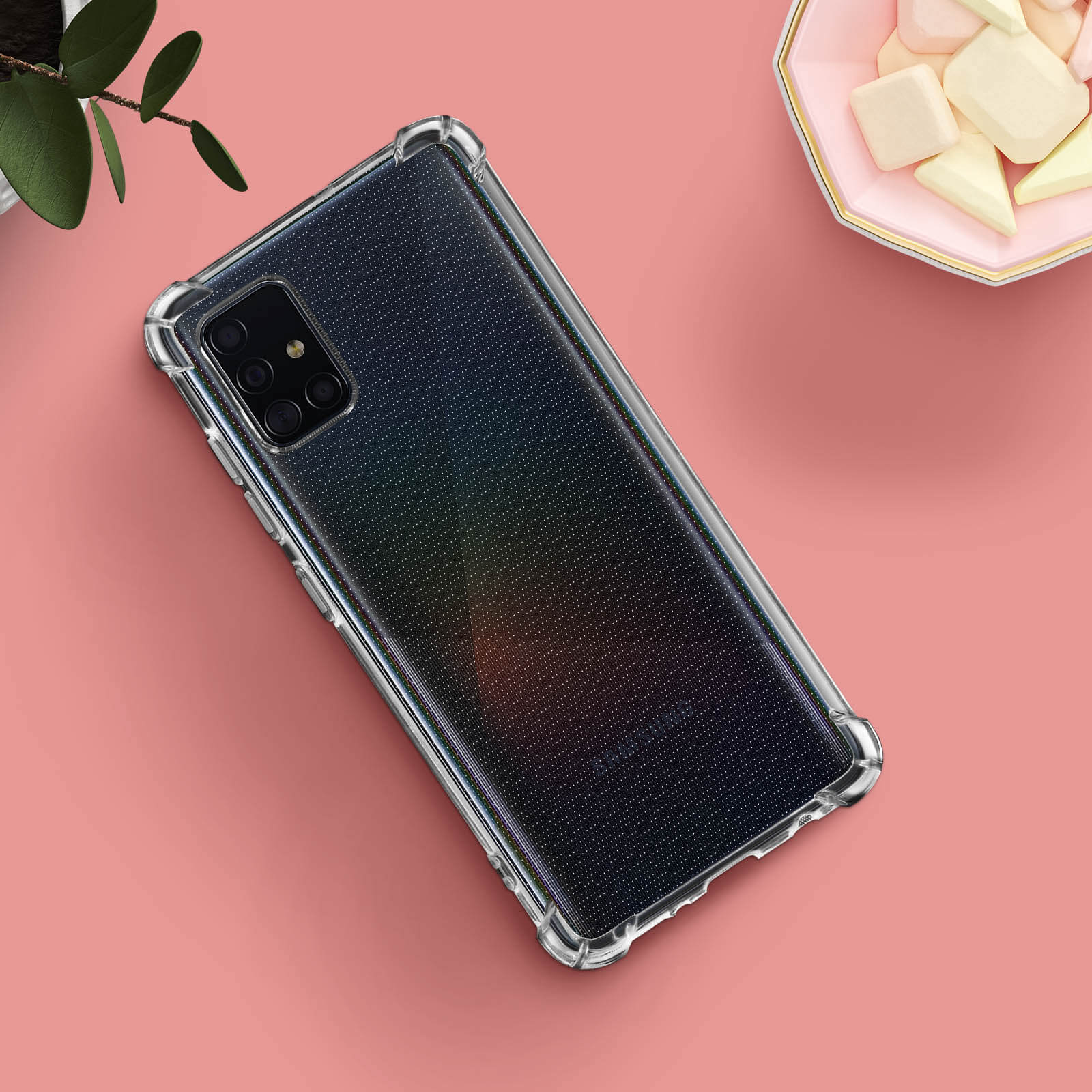 Telefono in custodia trasparente. Il telefono è su una superficie rosa con marshmallow.