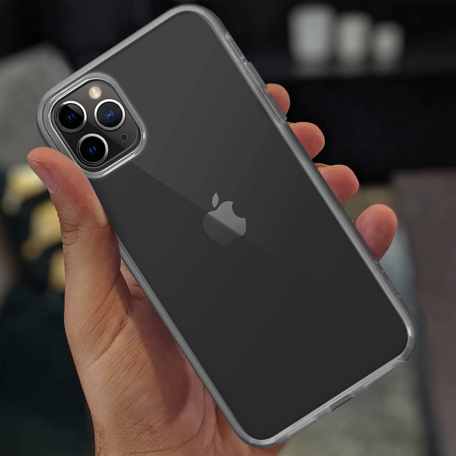 Un iPhone dans une coque transparente. Le téléphone est tenu dans une main. L'arrière-plan est flou.