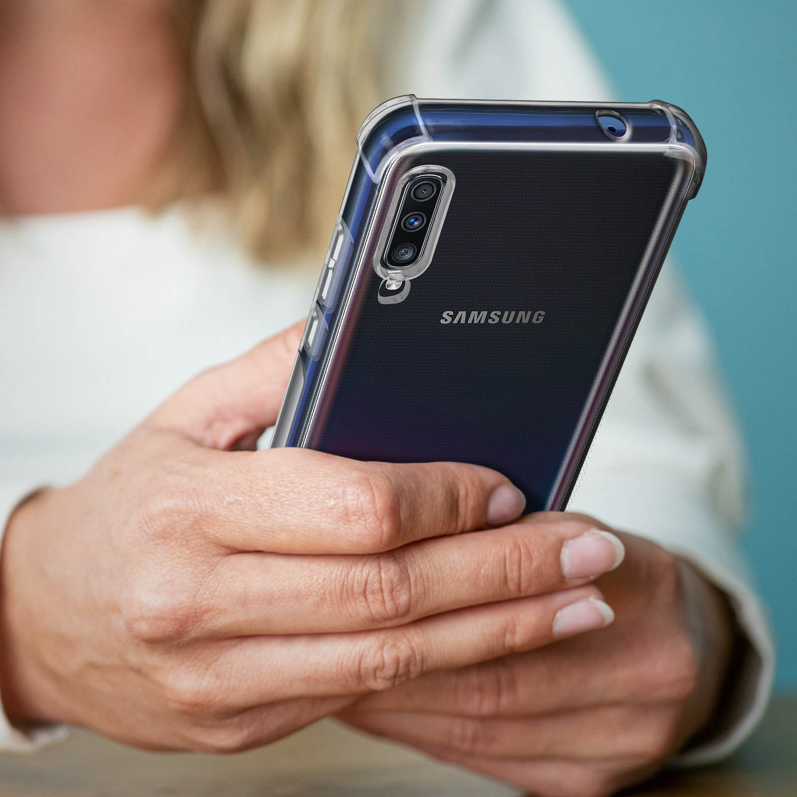 Una donna tiene una custodia trasparente per telefono Samsung su un telefono nero.