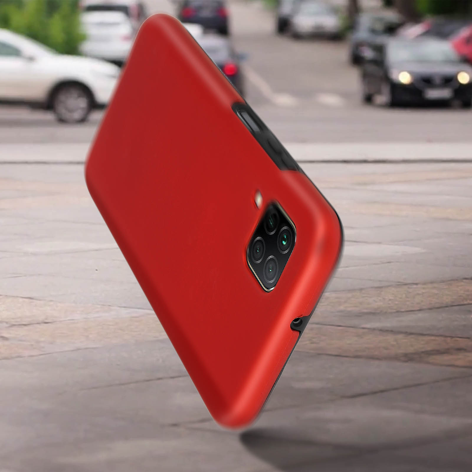 Een rode telefoonhoes, met de telefoon erin, tegen een wazige stedelijke achtergrond.