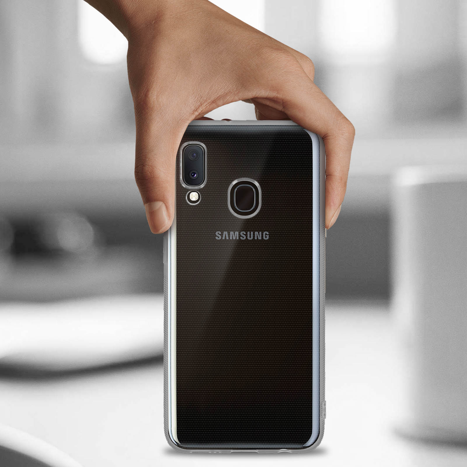 Mano che tiene un telefono con custodia trasparente. Il logo Samsung è visibile.