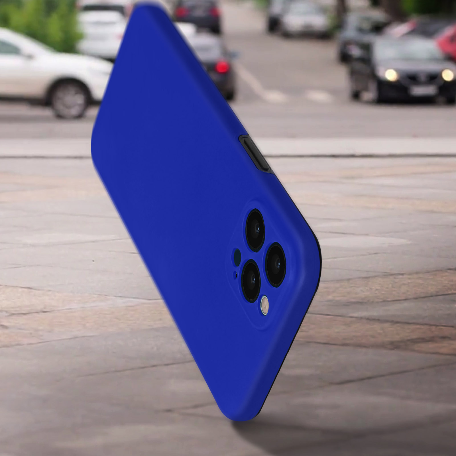 Een blauwe telefoonhoes die op een stoep ligt, met wazige auto's op de achtergrond. De hoes is blauw.
