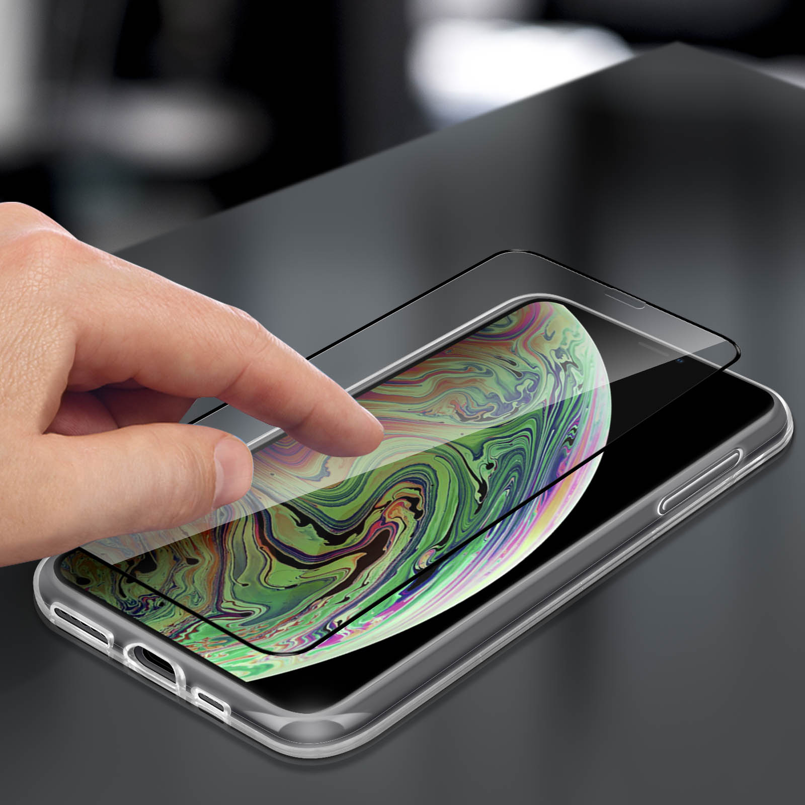 Mano che applica la protezione dello schermo su un telefono. Il telefono è su una superficie scura.