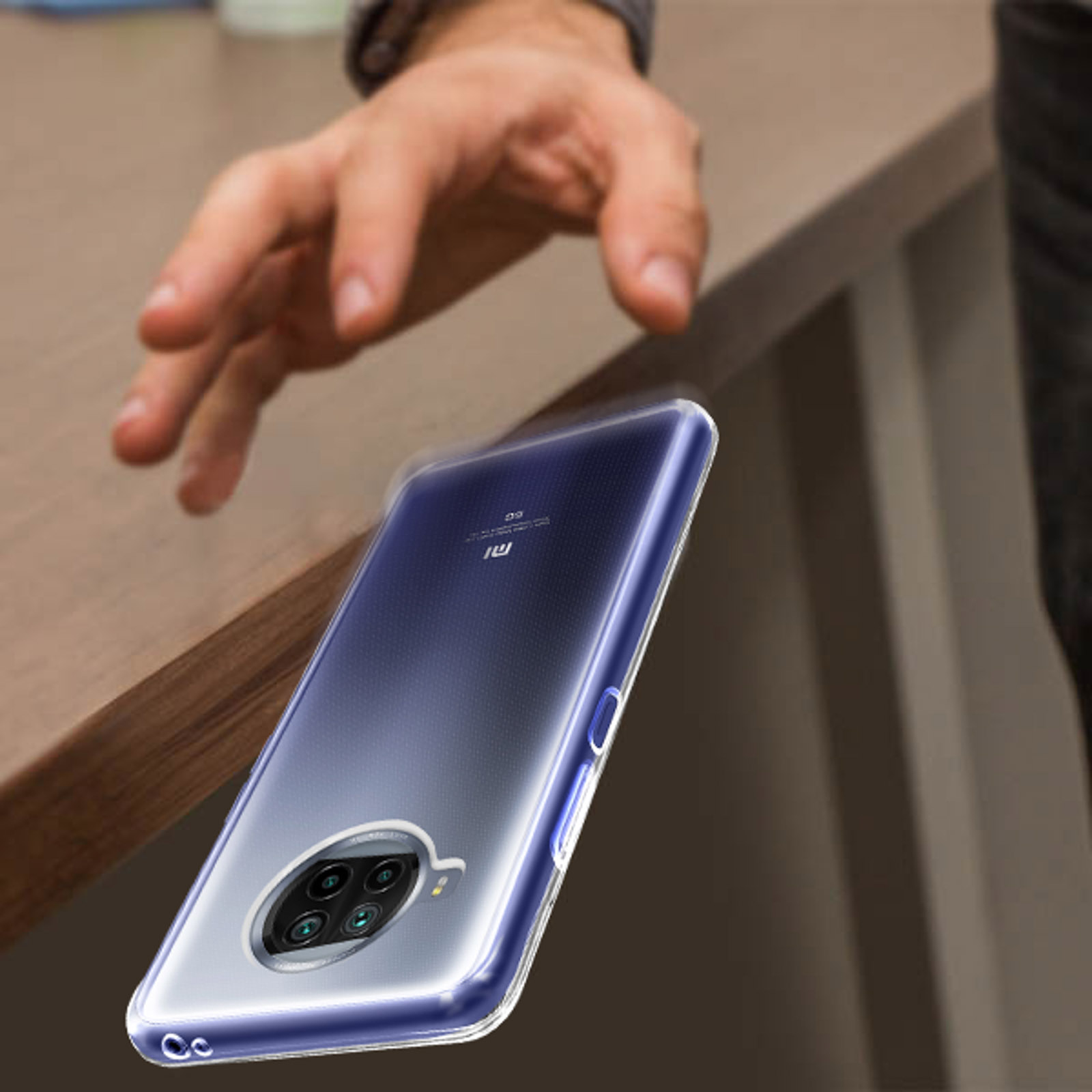 Mano che si allunga verso un telefono in una custodia trasparente. Il telefono è vicino a un tavolo. Lo sfondo è sfocato.