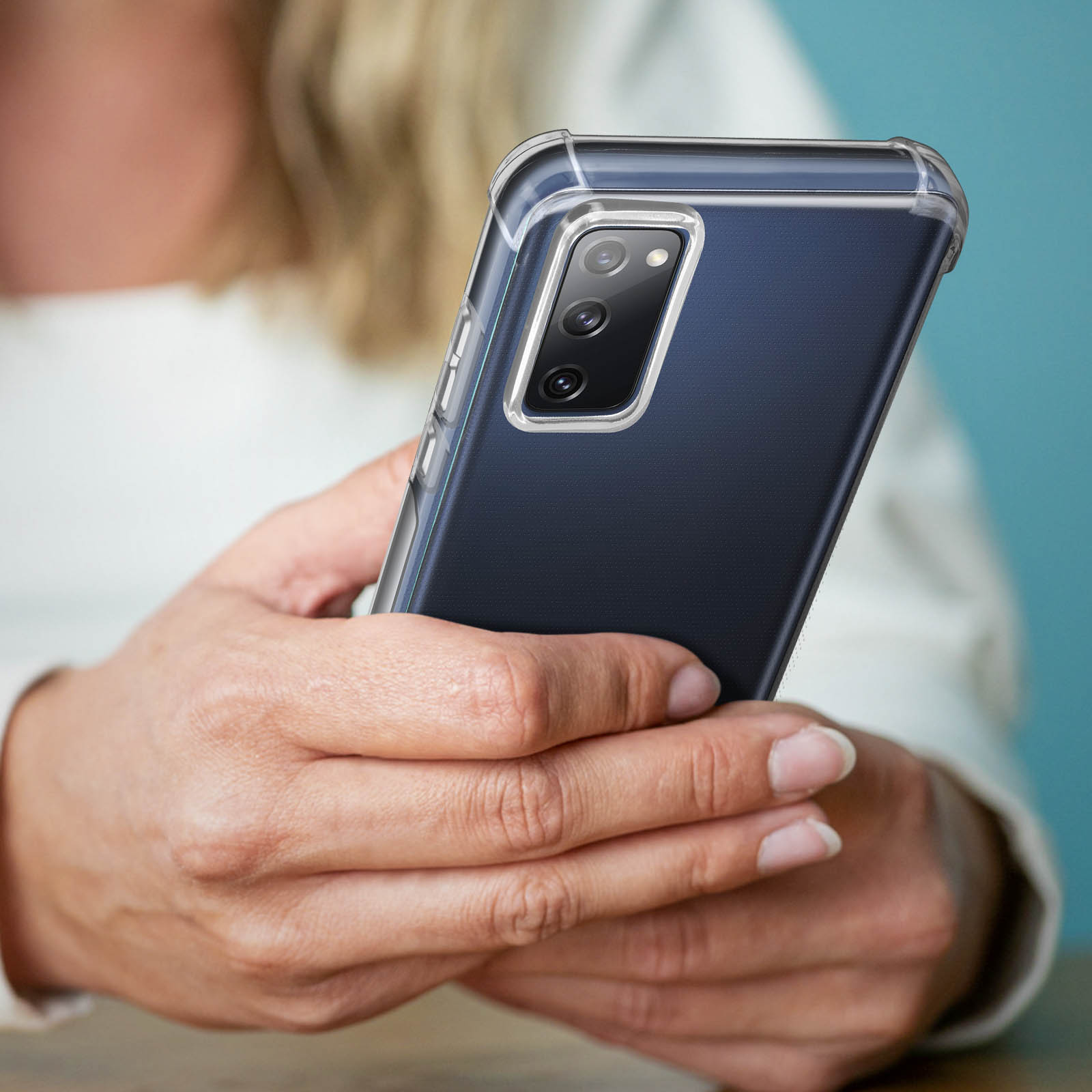 Telefono in una custodia trasparente tenuto in mano, che mostra la fotocamera e i pulsanti.