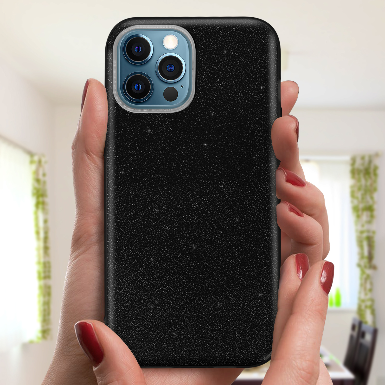 Mani che tengono una custodia nera per telefono. La custodia ha tre fotocamere. Sfondo sfocato.