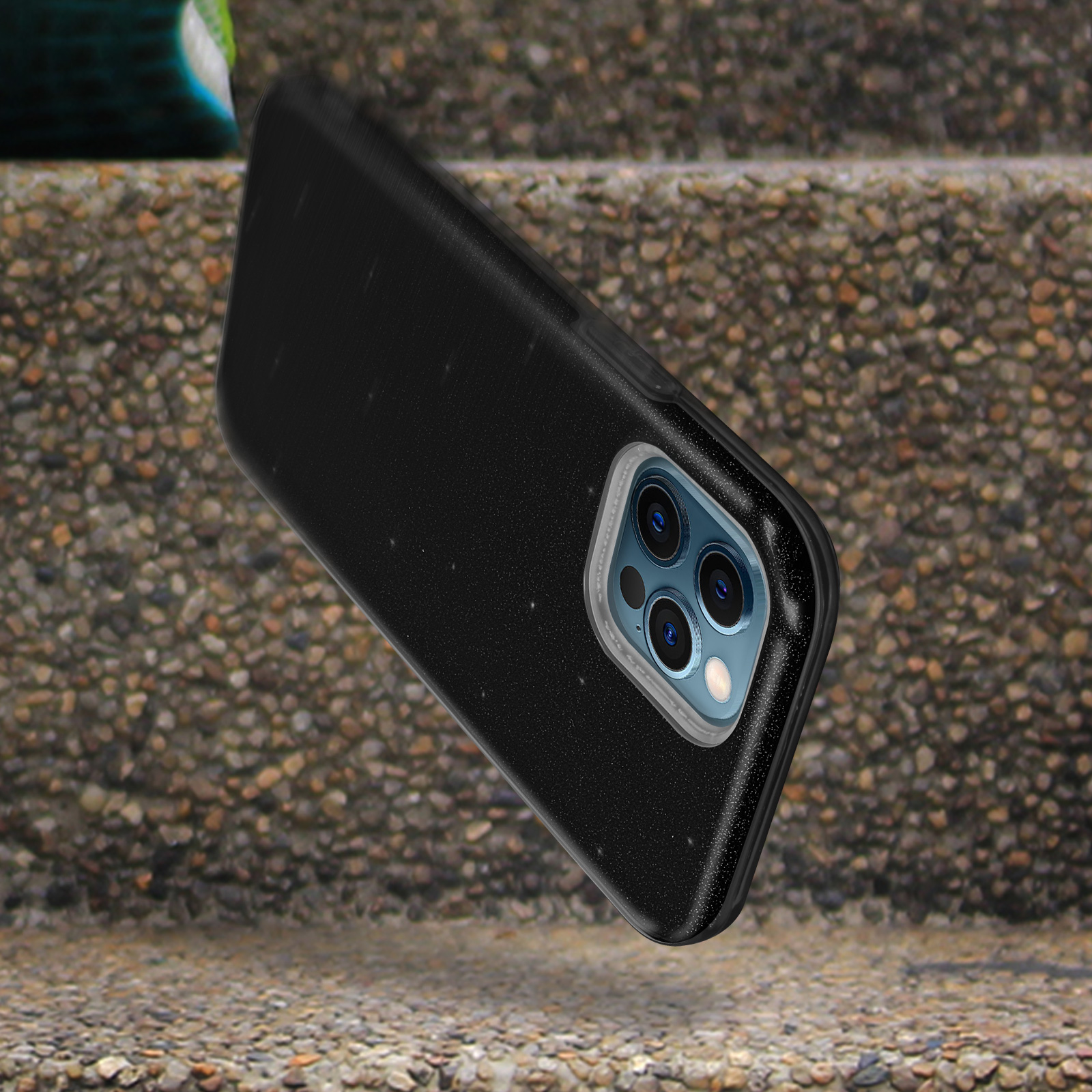 Una custodia nera che cade su una superficie strutturata. Il telefono ha una fotocamera a tre lenti.
