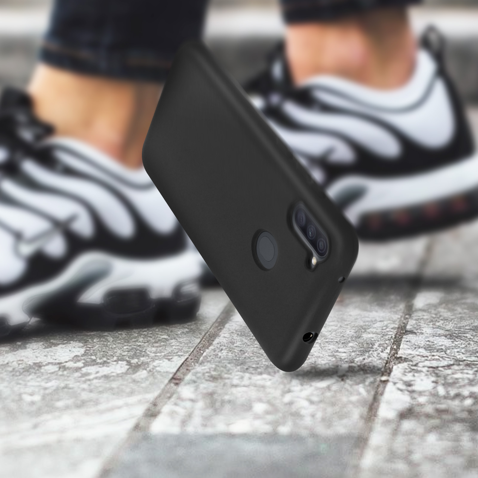 Custodia per telefono nera con fotocamera. Lo sfondo mostra gambe e scarpe da ginnastica.