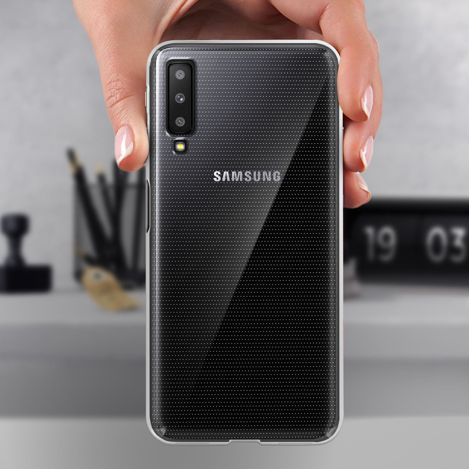 Hand hält ein Telefon mit transparenter Hülle, Samsung-Logo sichtbar.