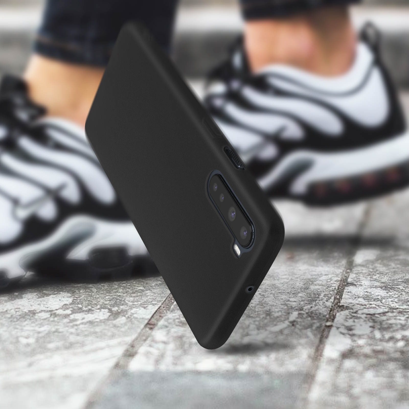 Custodia nera per telefono con ritaglio per fotocamera a tripla lente, tenuta da una persona su superficie.