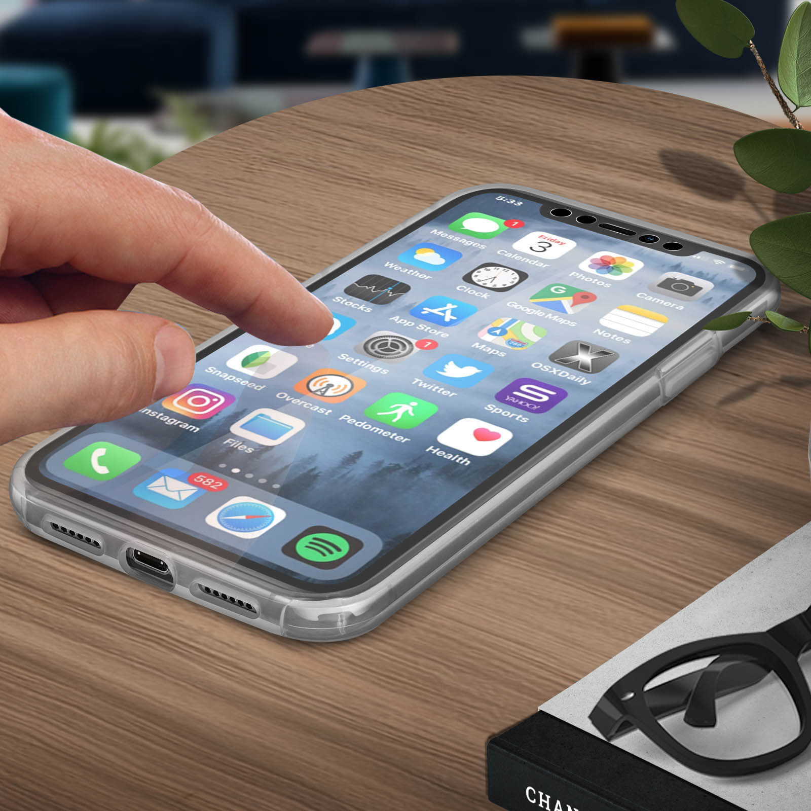 Een telefoon met apps. Vinger raakt het scherm. Bril en boek op de achtergrond.