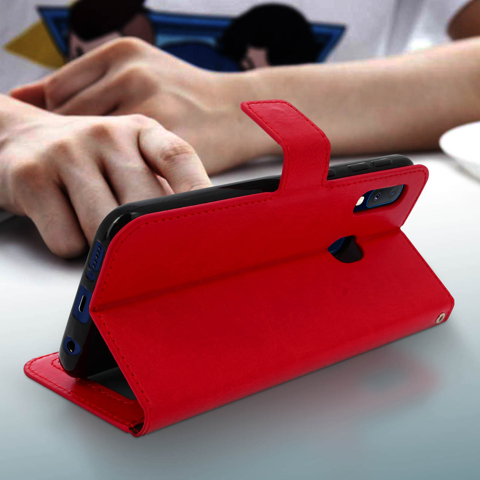 Custodia per telefono rossa aperta, che mostra il telefono e gli slot per schede, su un tavolo.
