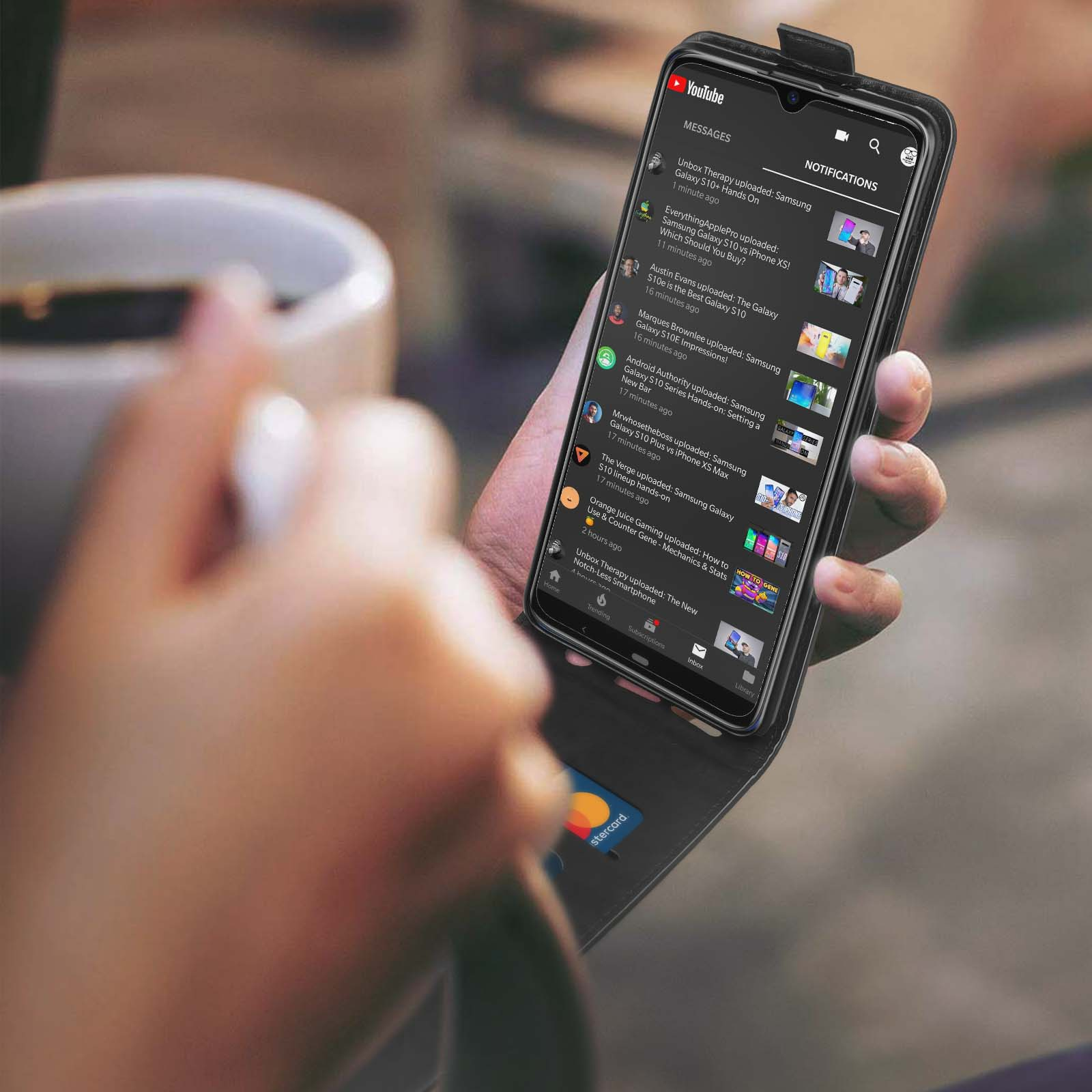 La mano di una persona tiene una custodia per telefono con un telefono all'interno. Il telefono mostra un video di YouTube.