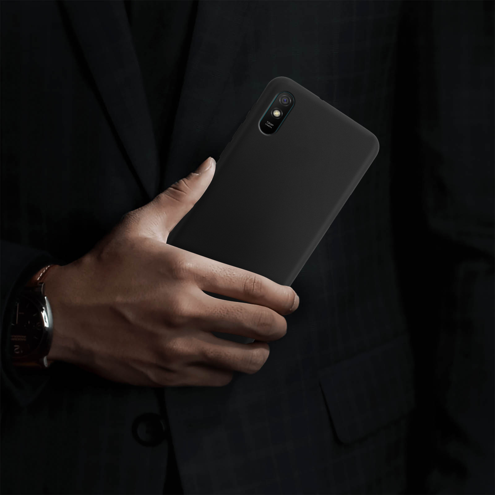 Una persona tiene in mano un telefono nero in un ambiente buio. Il telefono ha una custodia.